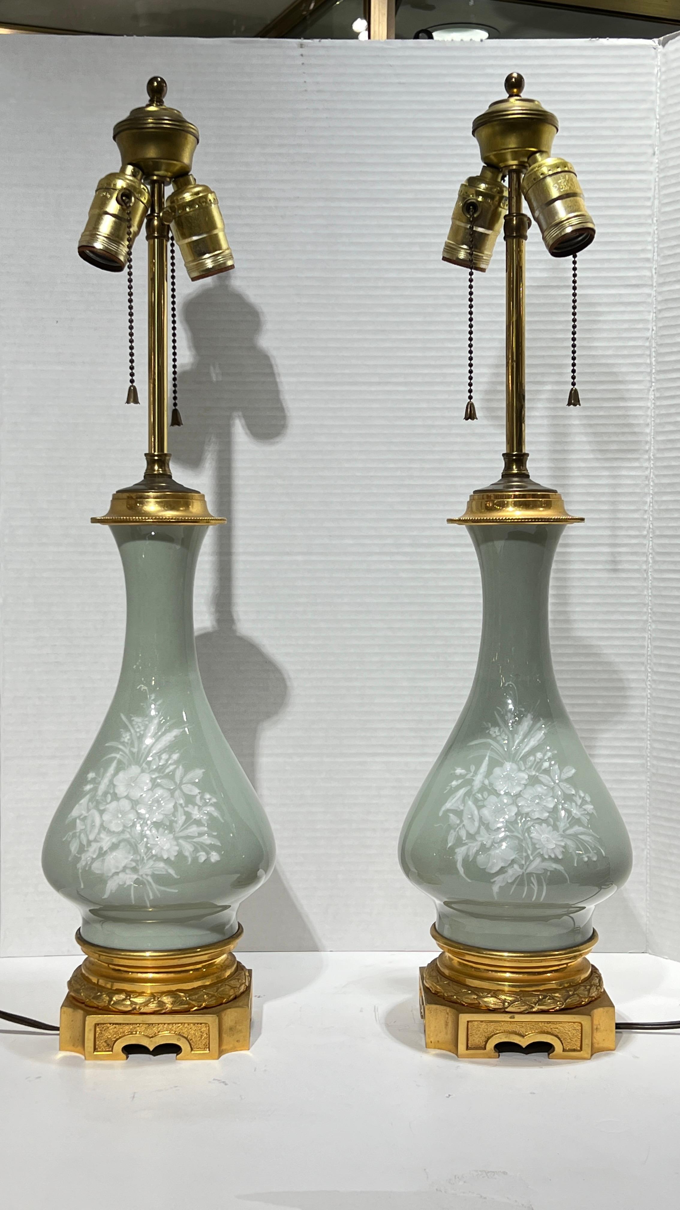 Pair of French 19 century celadon green porcelain vases with white floral pate-sur-pate designs, mounted on gilt bronze pedestals with sockets and wiring added.