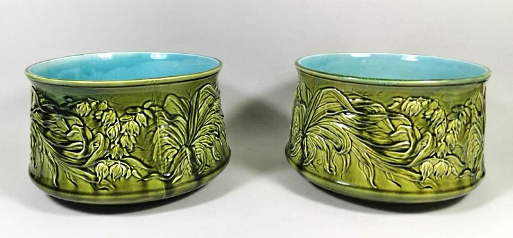 Pair of barbotine ceramic cachepots; they are magnificently enriched with elaborate floral decorations; the green colour shade is particularly well guessed and contrasts well with the celestial interior; they have a water drainage hole at the