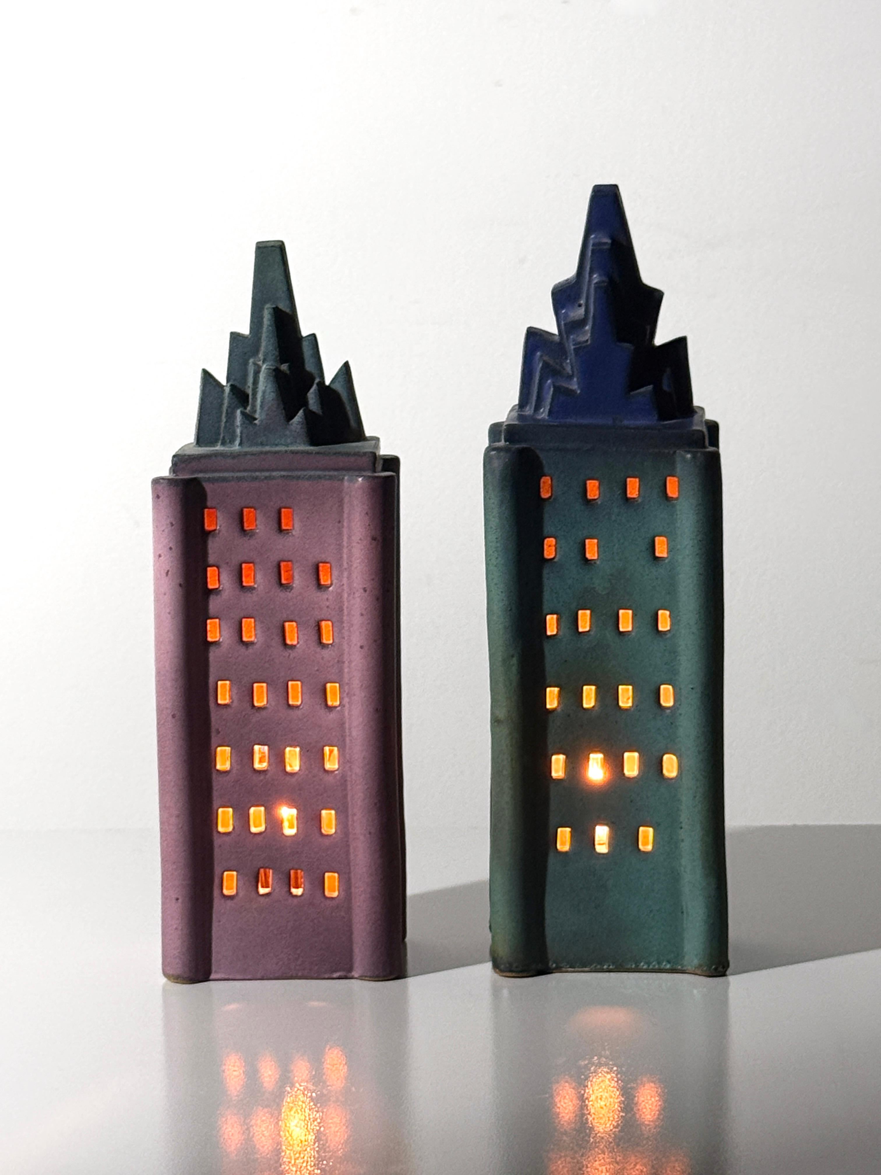 A pair of unique sculptural table lamps by Detroit ceramic artist Doug Spalding circa 1990s

Two ceramic buildings in matte glaze with pierced windows emitting a dim ambient glow

Great for bedside lamps or a sculptural accent in any modern
