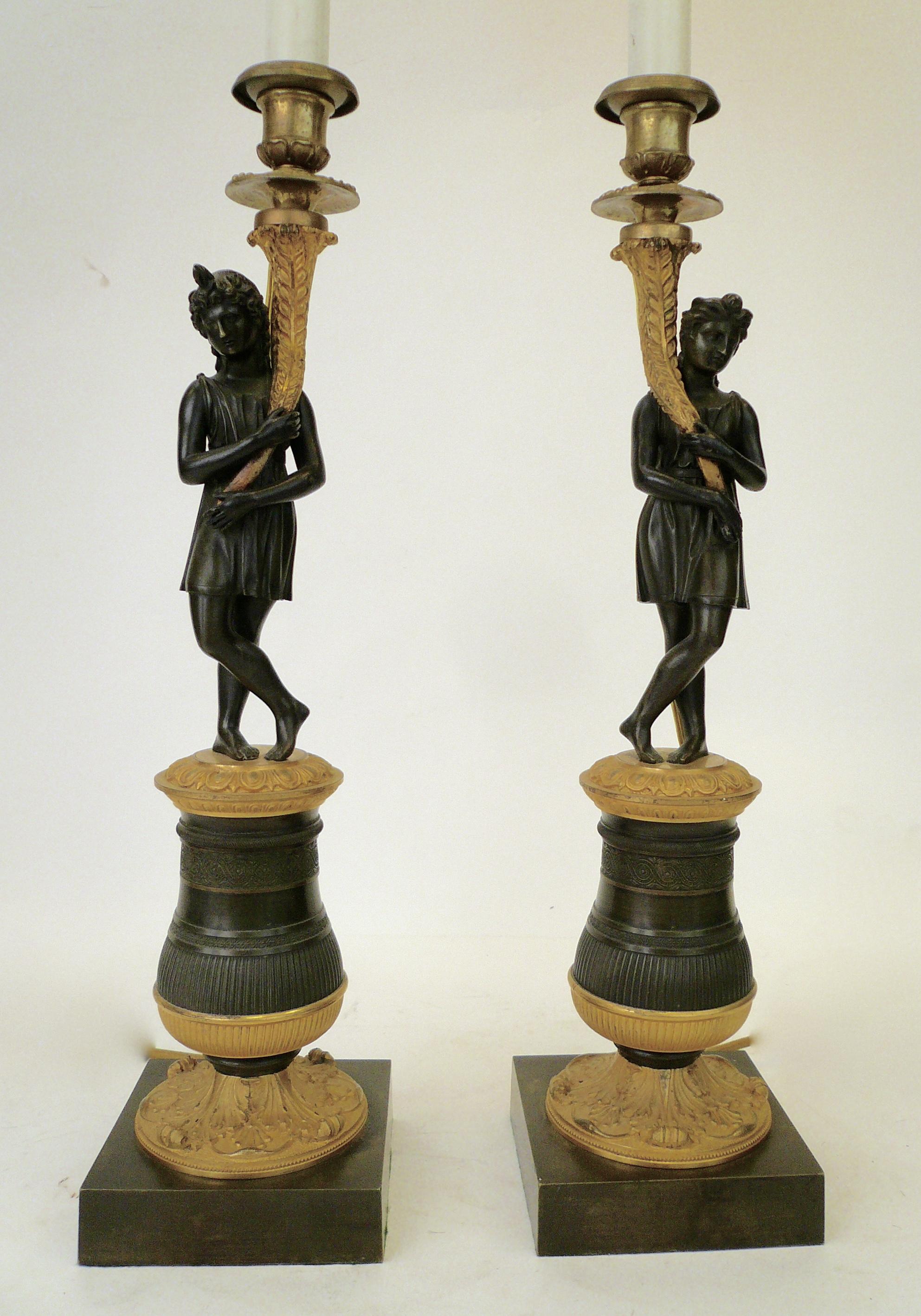 This handsome pair of lamp bases feature classical figures holding cornucopia. They stand on plinth bases that feature acanthus leaf and egg and dart motifs.