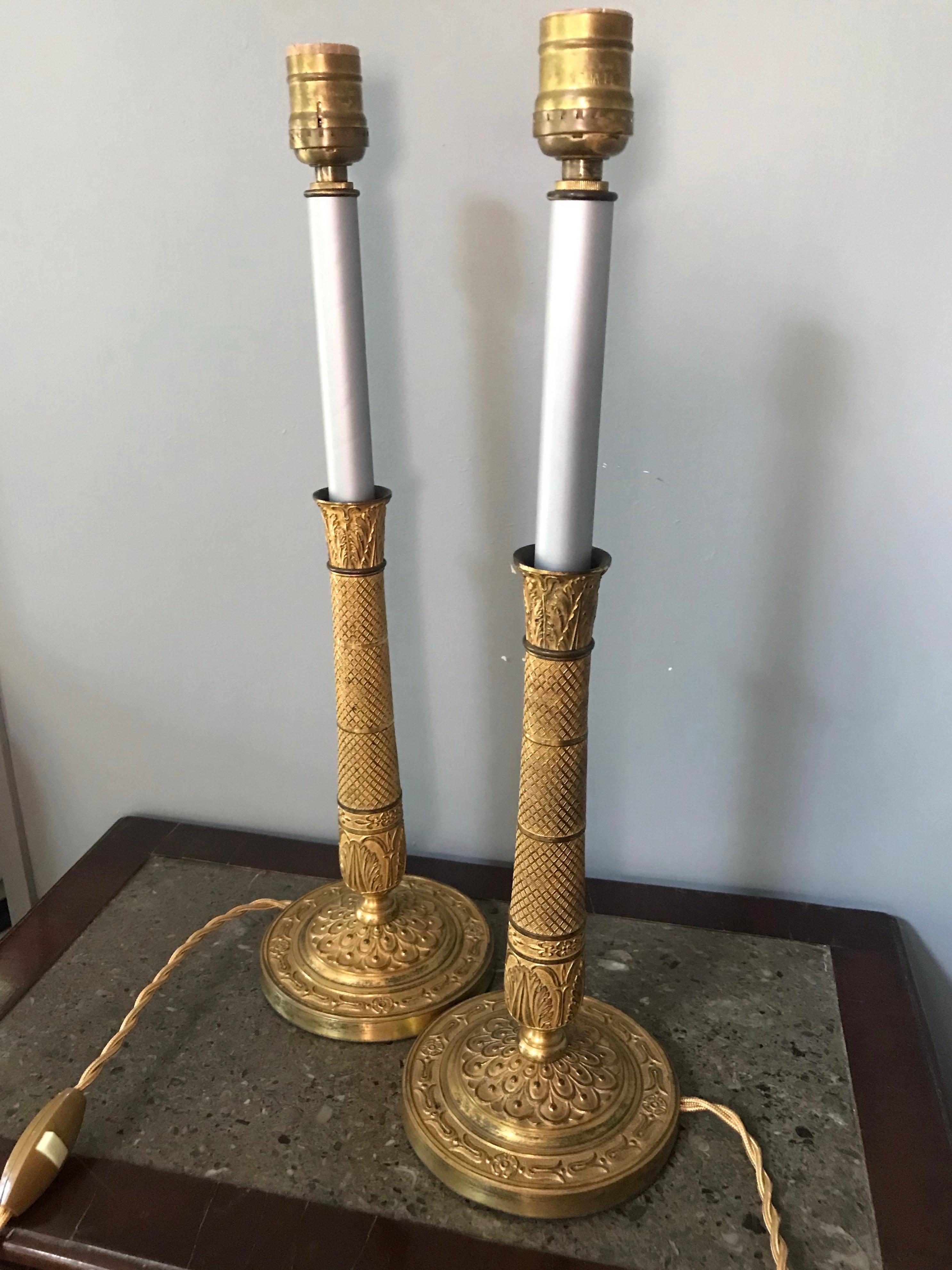 Pair Charles X Ormolu candlestick lamps. Fine pair finely chased gilt metal candlesticks with grey painted candle sleeves above anthemion capitals with diapered banded shafts ending in circular bases with neoclassical decoration; with newly