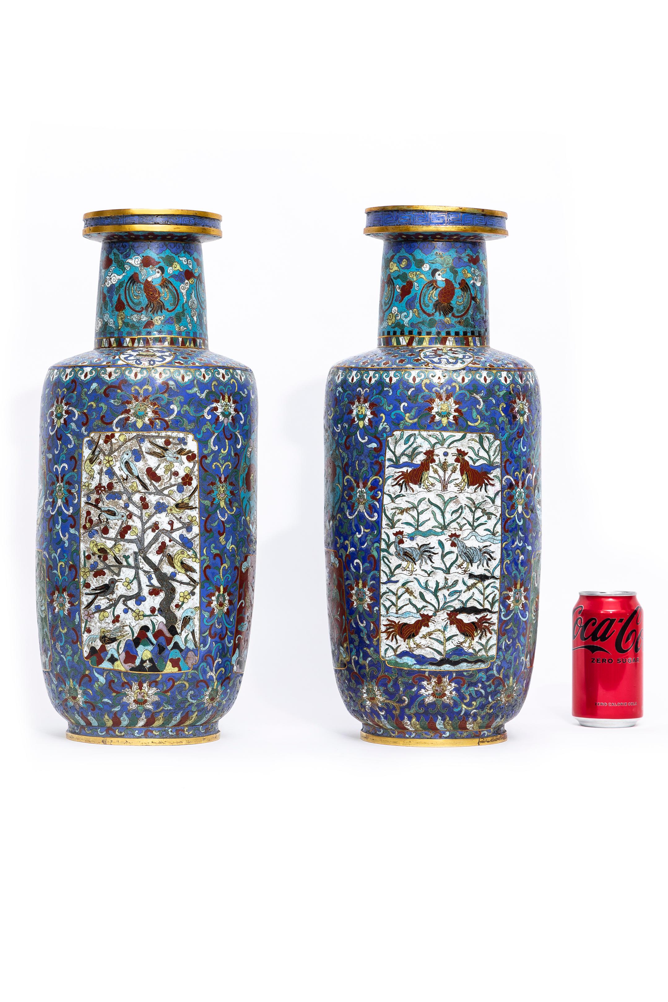 A Gorgeous Pair of Antique Chinese 19th Century, Qing Dynasty, Cloisonne Multi-Cartouche Blue Ground Gu Form Vases.  These vases feature a surface detailed with birds, plants, and clouds inhabiting an abstracted landscape. Organized into several