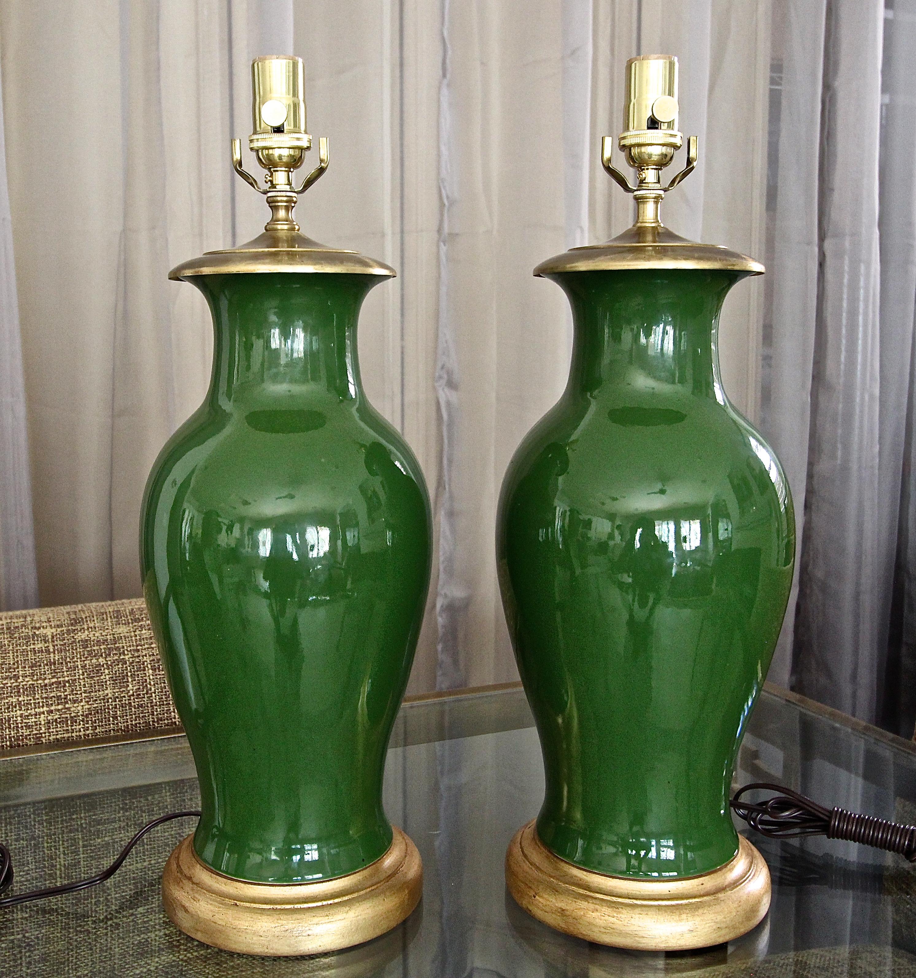 Pair of Chinese forest green porcelain baluster form vases mounted on gilt turned wood lamp bases. Newly wired with new 3 way brass sockets and cords. Vase portion is 14.5