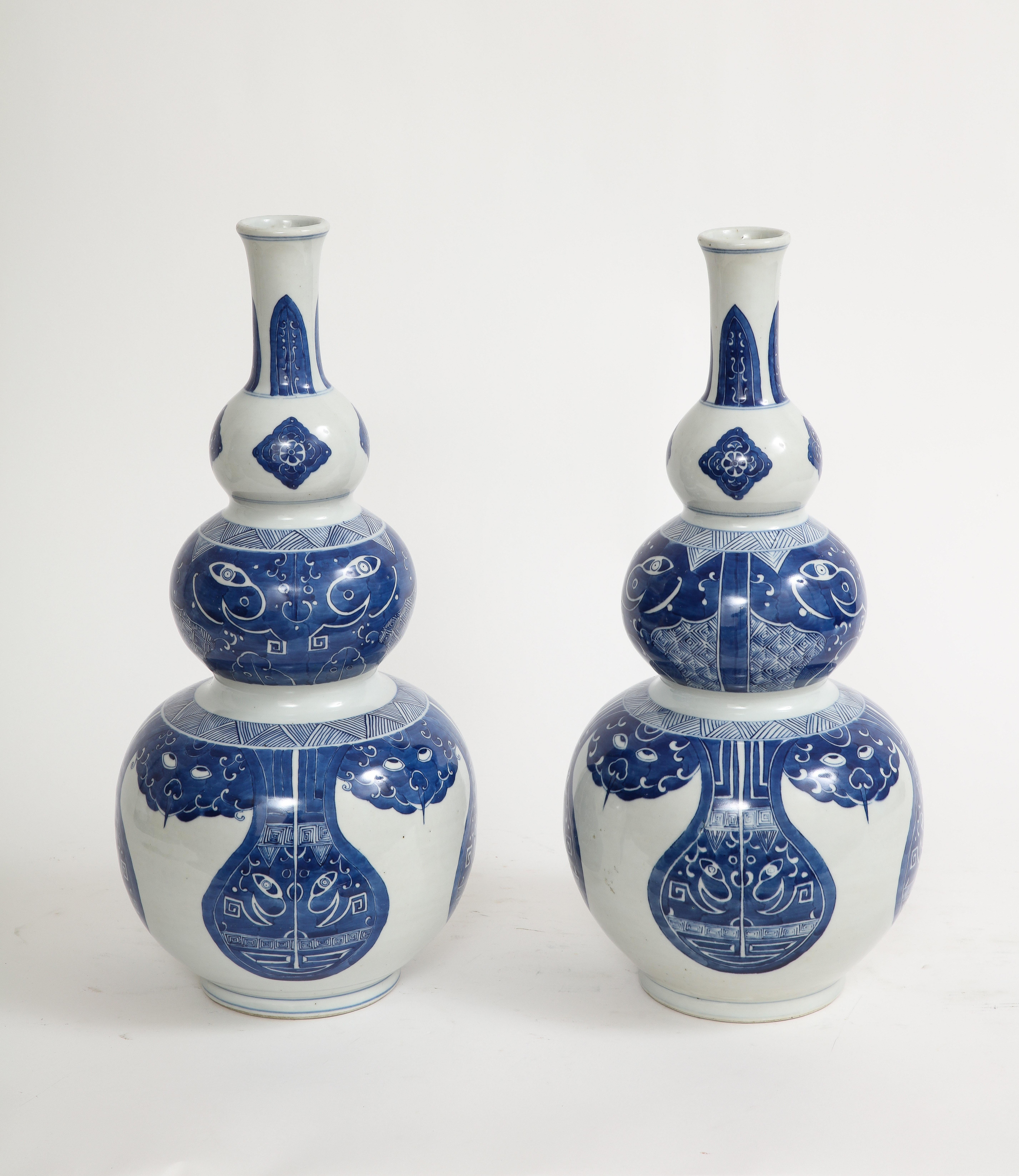 A pair of blue and white triple-gourd 'Taotie' vases, Qing Dynasty, 19th century. A pair of blue and white triple-gourd 'taotie' vases. The base of each with an apocryphal Kangxi six-character mark in underglaze blue. Triple gourd Chinese vases are