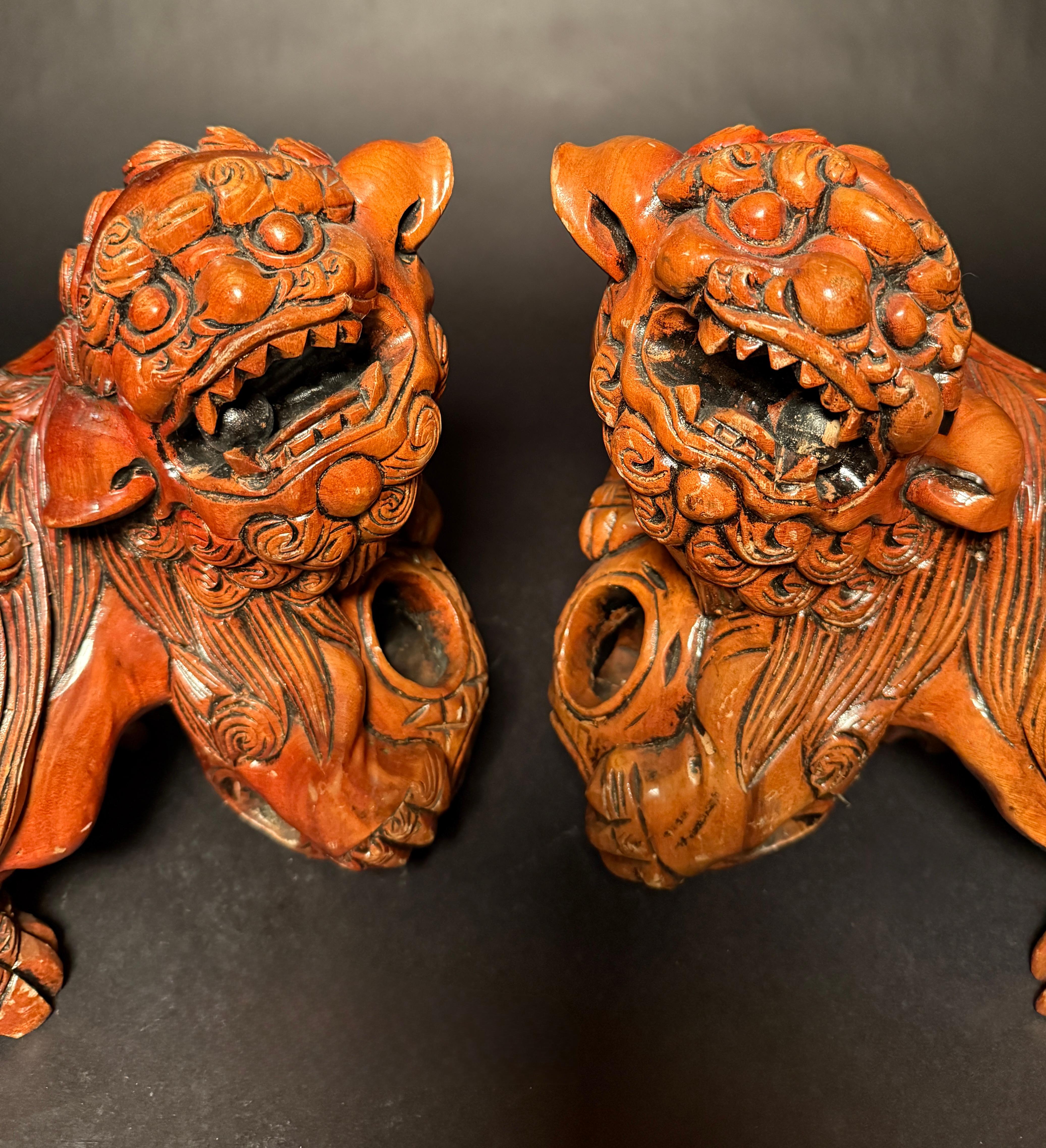 A fine pair of Chinese carved hardwood figures of Foo dogs from mid-20th century. These exquisite hand-carved wooden Foo dogs display the exceptional craftsmanship of Chinese artisans.  Each Foo dog is well carved, capturing the regal and protective