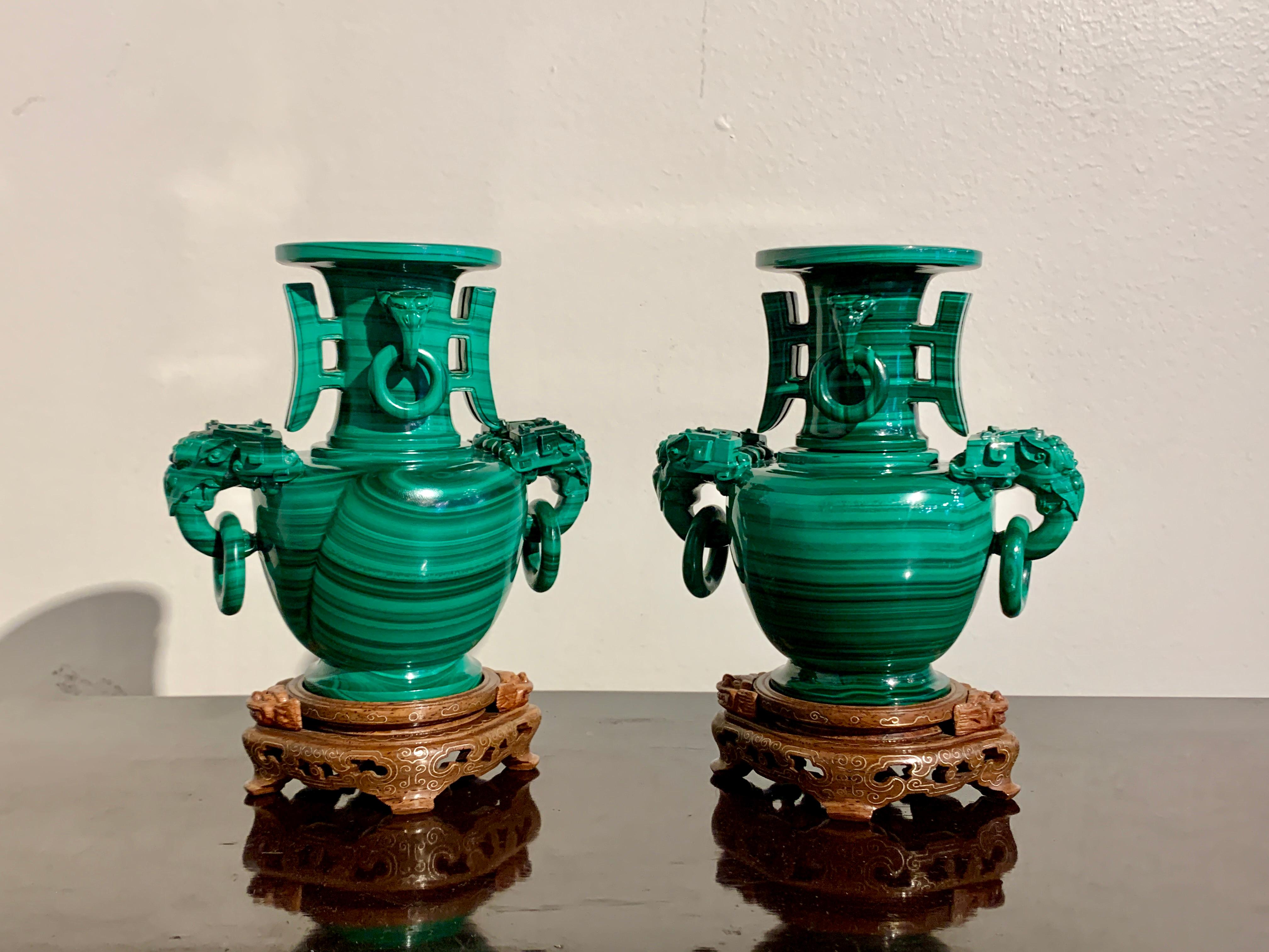 A fine and well carved Chinese pair of carved malachite vases with loose ring handles and fitted bases, Republic Period, mid 20th century, China.

The vases carved from solid malachite of exceptional color and featuring spectacular striations. The