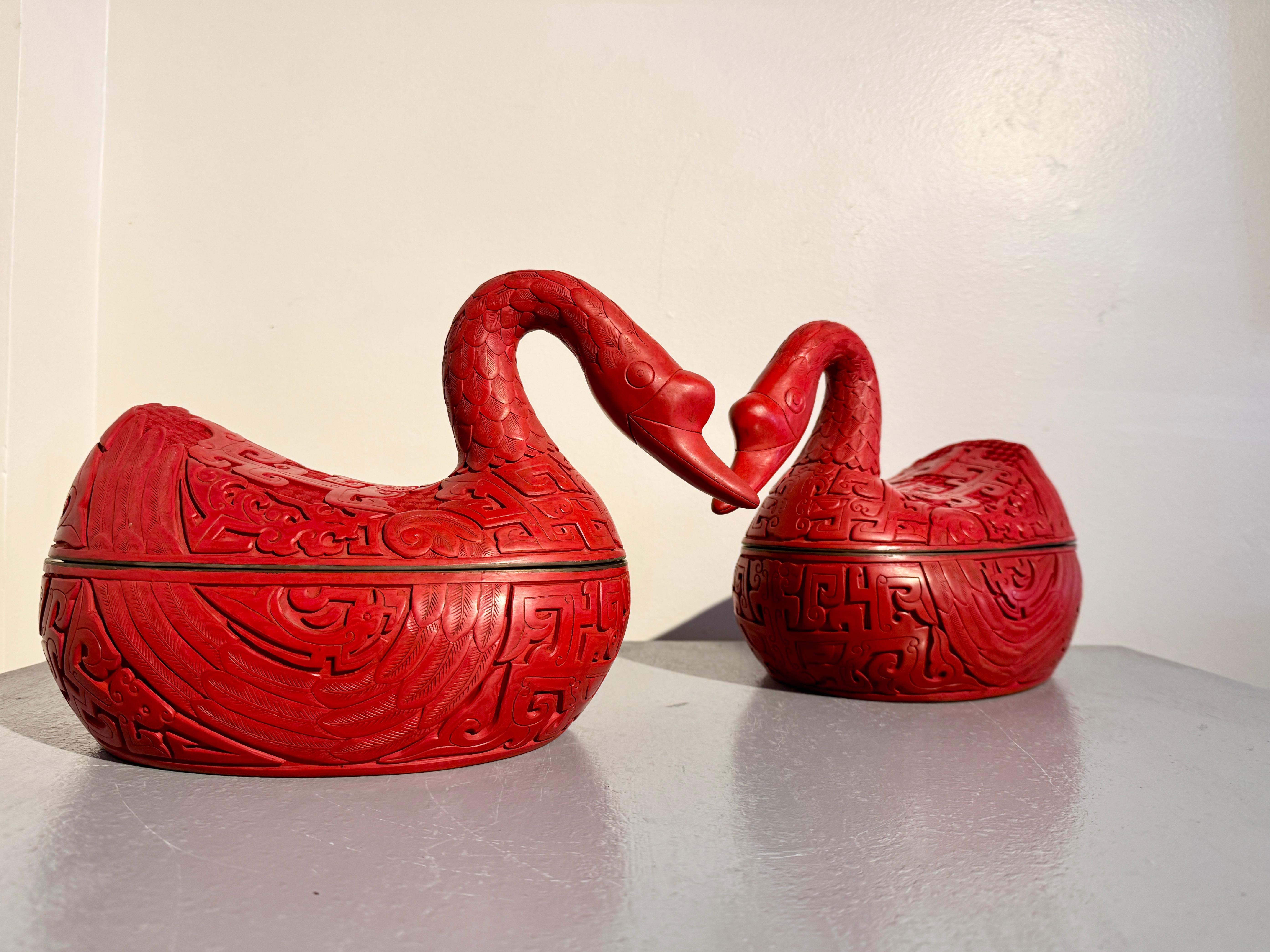 A fabulous pair of Chinese carved red lacquer boxes in the form of ducks or geese, mid 20th century, China.

Crafted of carved red lacquer (similar to cinnabar lacquer) over wood, with brass rims, the duck are portrayed in a roosting position, their