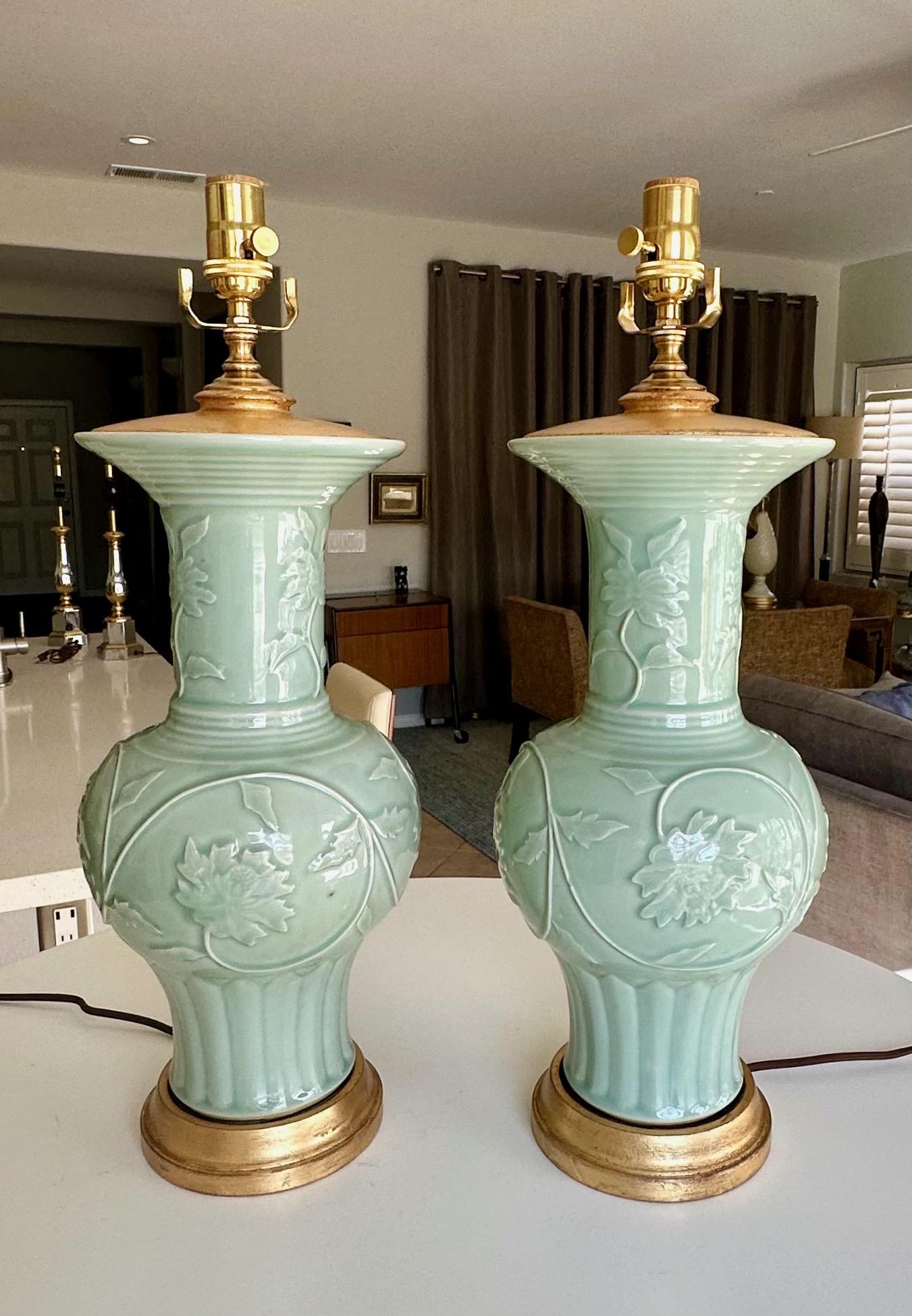 Paire de lampes de table en porcelaine chinoise asiatique céladon vert, fleurs et feuillages sculptés en relief. Chacun est monté sur des bases en bois doré, avec un bouchon de vase assorti. Le câblage a été refait à neuf avec des prises à 3 voies