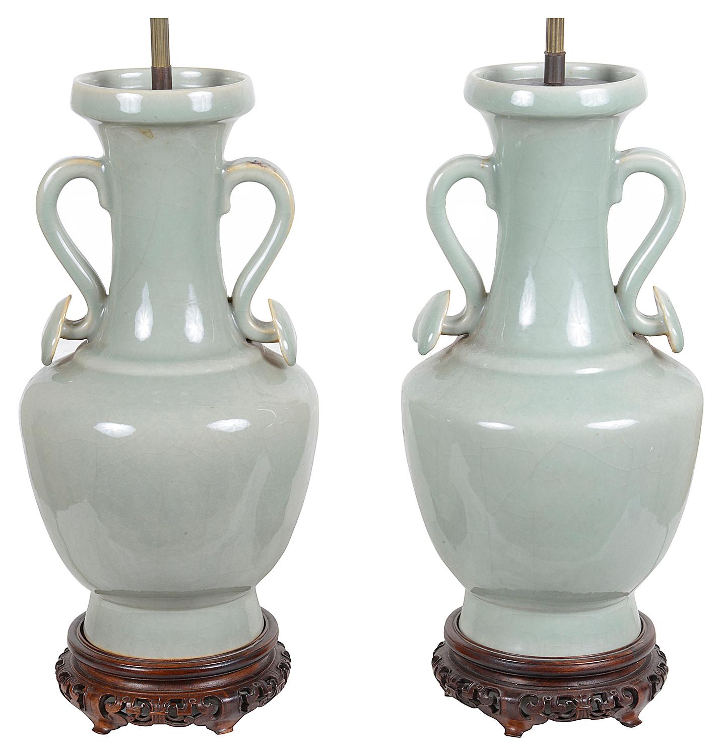 A very decorative pair of 18th century style Chinese Celadon porcelain two handled vases / lamps, raised on carved pierced hardwood stands, circa 1920.