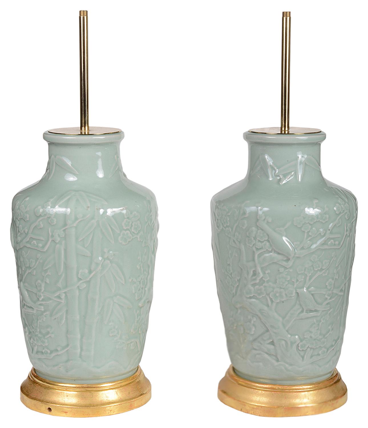 Paire de vases / lampes en porcelaine chinoise céladon de bonne qualité, chacun avec une décoration en relief représentant des oiseaux et des arbres en fleurs. Montés sur des socles en bois doré.