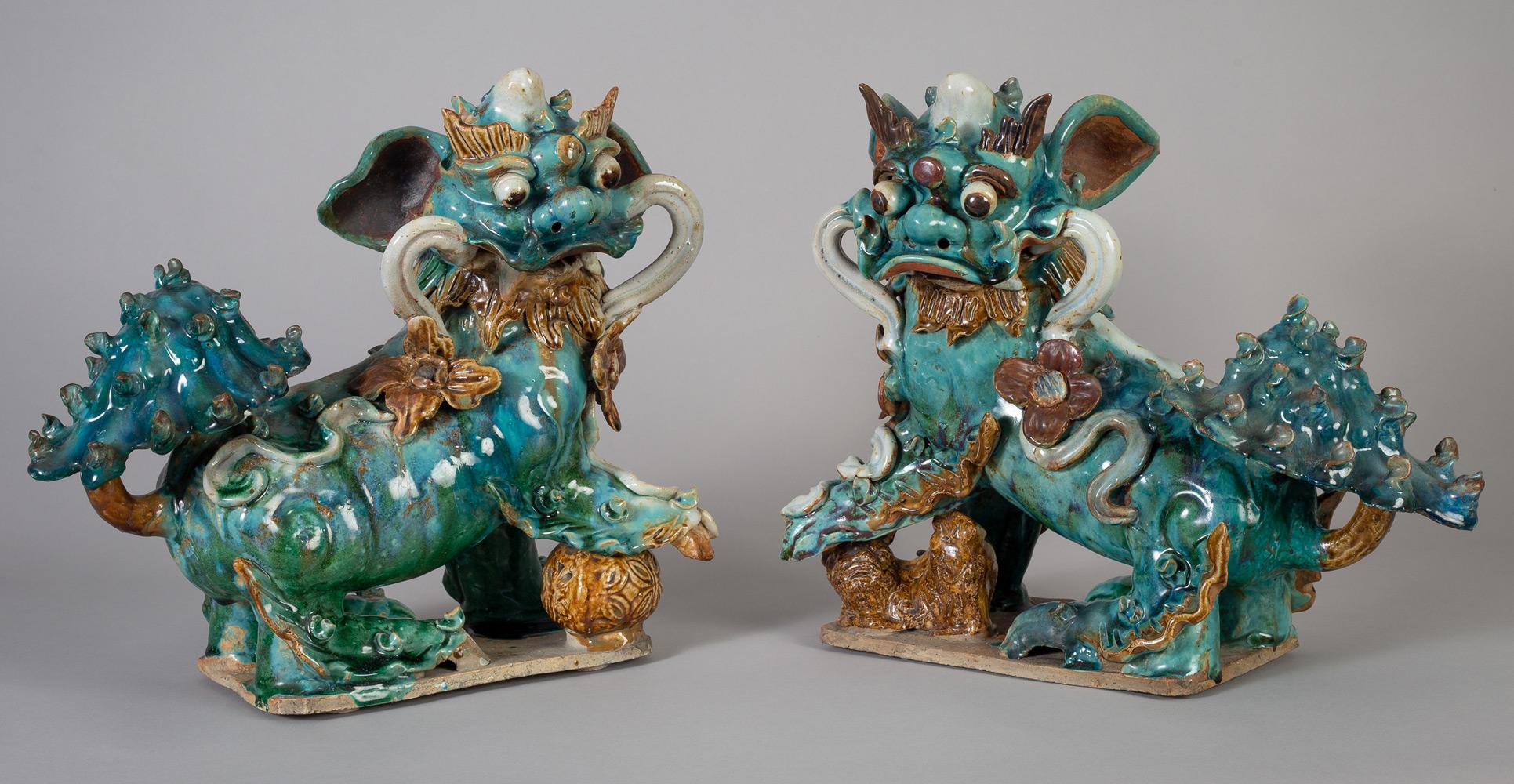 Pair of large fierce-looking and colorful Chinese Ming style pottery Buddhistic lions or foo dogs in a Sancai glaze (three colors). They are finely modeled, the female with a cub under her foot symbolizing fertility and the male with an orb under