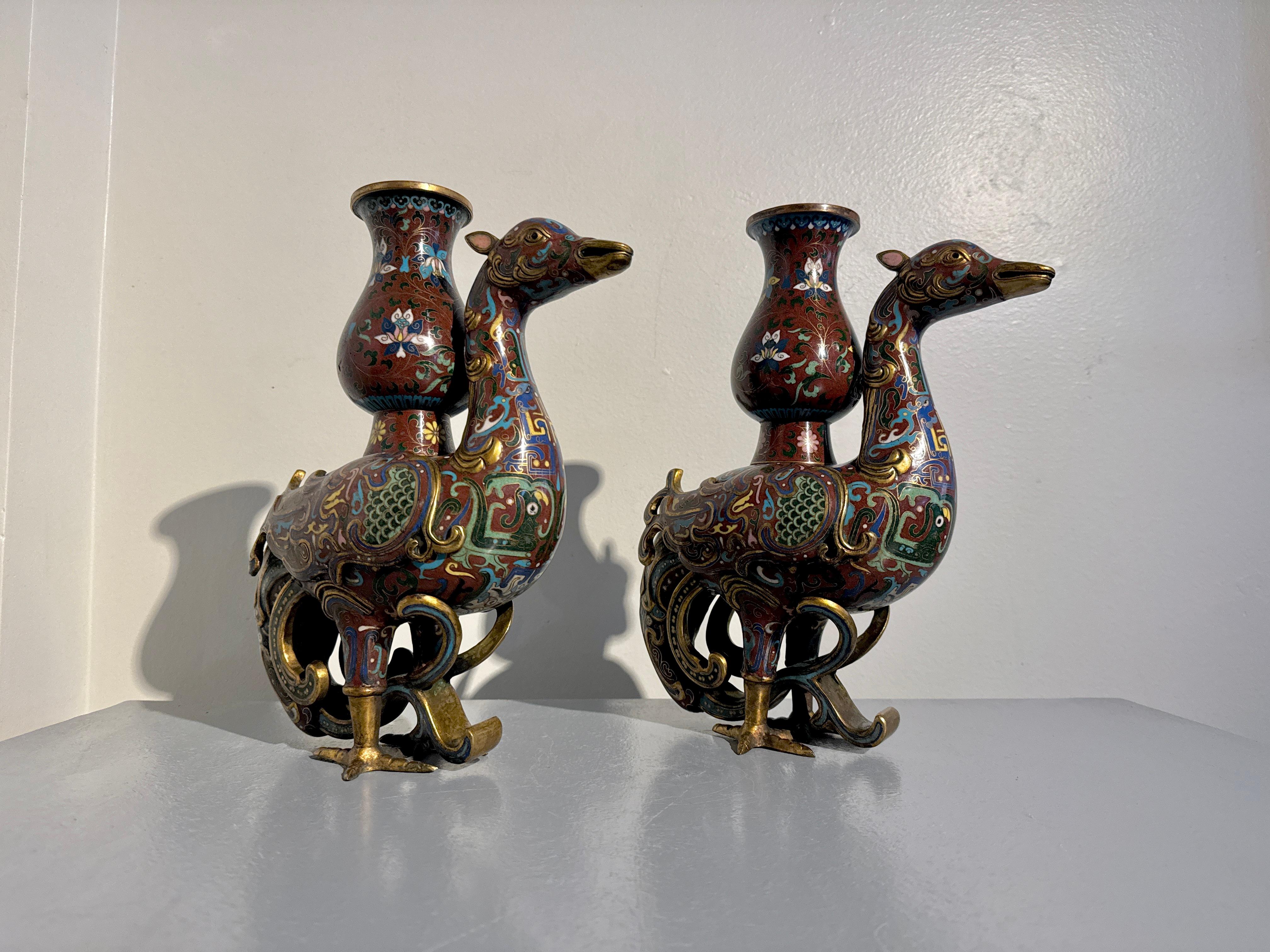 Paire impressionnante de vases zun en cloisonné de forme phénix, fin de la dynastie Qing, vers 1900, Chine.

Paire de vases en cloisonne sur fond rouge, en forme d'oiseaux phénix mythiques portant sur leur dos des vases de forme zun. Ces oiseaux
