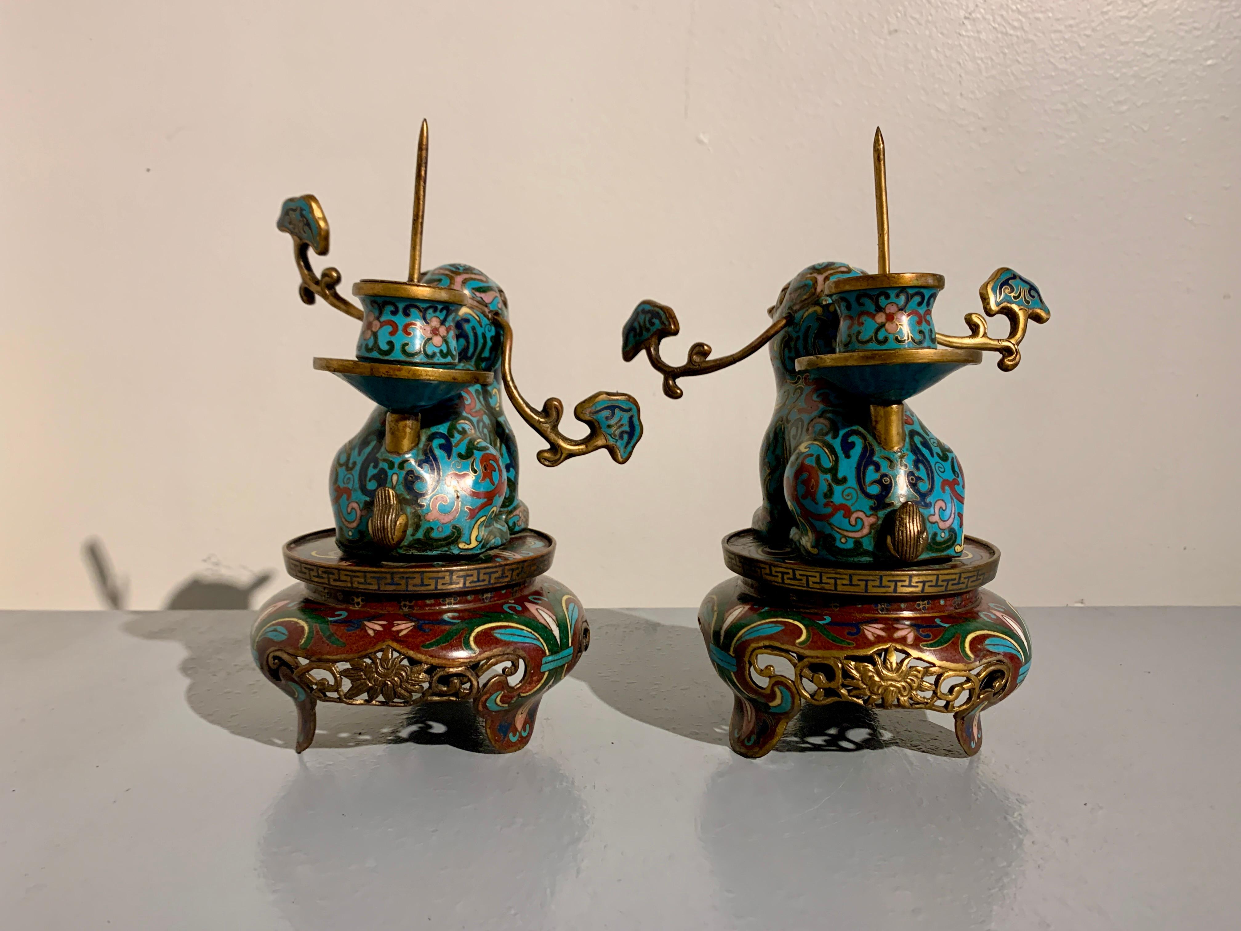A delightful pair of Chinese cloisonne candlesticks in the form of tapirs, Late Qing Dynasty, circa 1900, China.

The charming pair of candlesticks each crafted as a tapir seated upon a round table-form pedestal. The tapirs rest upon their haunches,