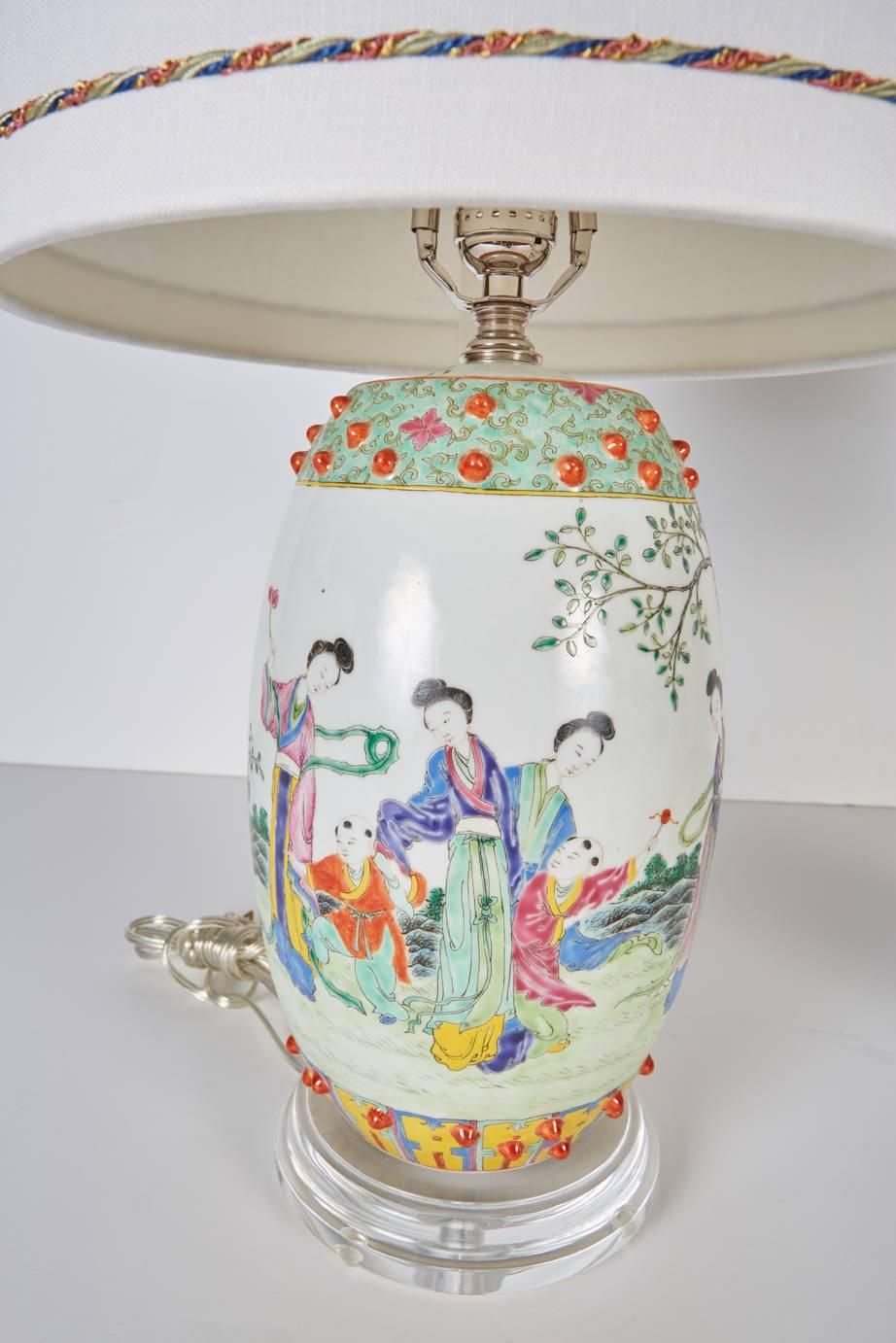 Pair of vintage Chinese porcelain drum shaped decorative porcelains now custom mounted as lamps with custom shades. Porcelains rest on custom Lucite bases. Custom shades are in white silk trimmed with blue, celadon, coral and metallic gold colored