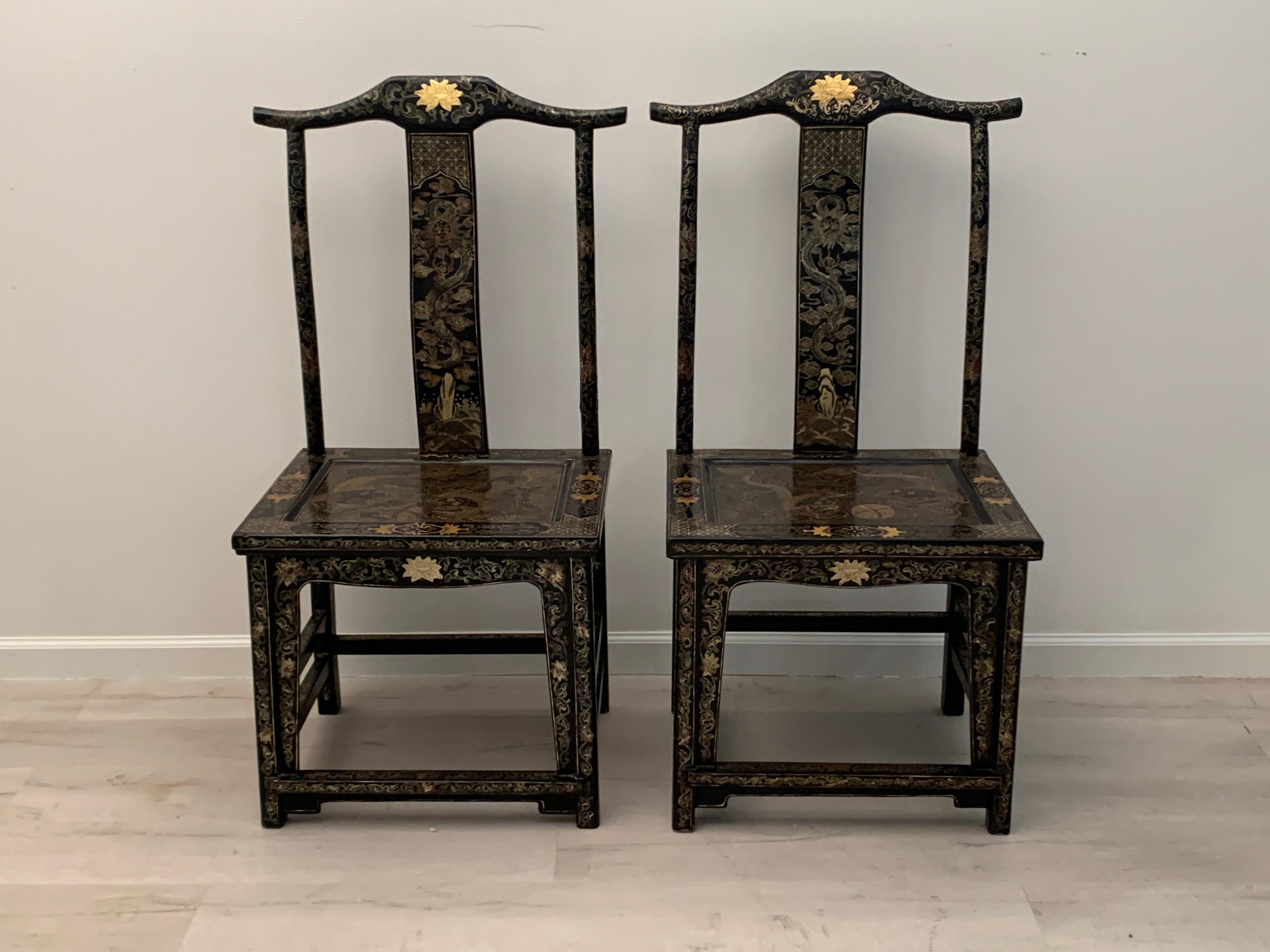A stunning pair of Chinese black lacquer and gilt painted official's hat side chairs, made for the export market, mid 20th century, China.

The pair of side chairs of yoke back form, and decorated with polychrome and gilt painted designs on a