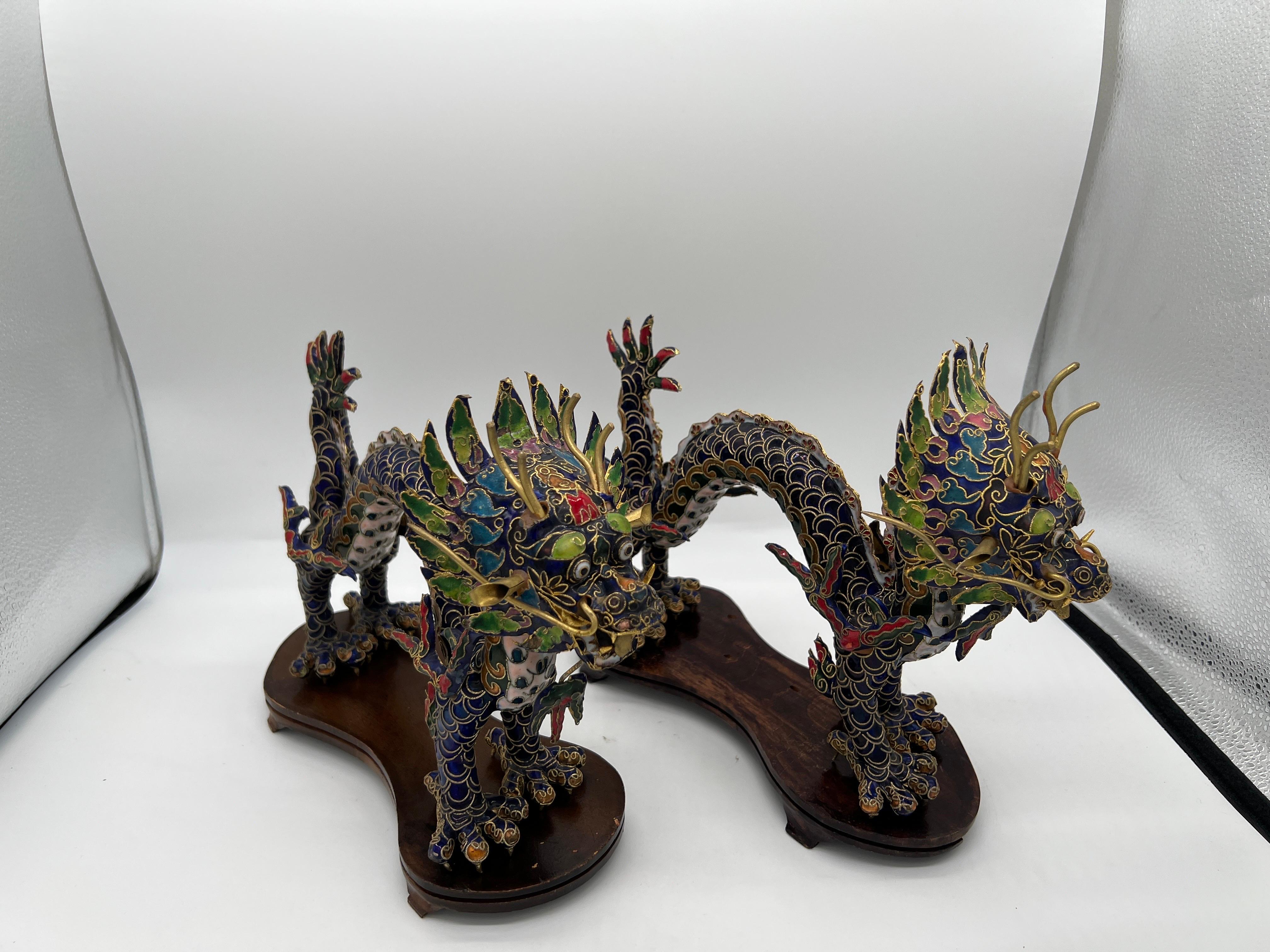Chinese, 20th century.

A pair of Chinese export style cloisonne dragon figurines on stands. Each dragon is detailed with brass wiring and hand enamel decorated across the surfaces. Chinese dragons are often a sign of good luck and power. Dragons