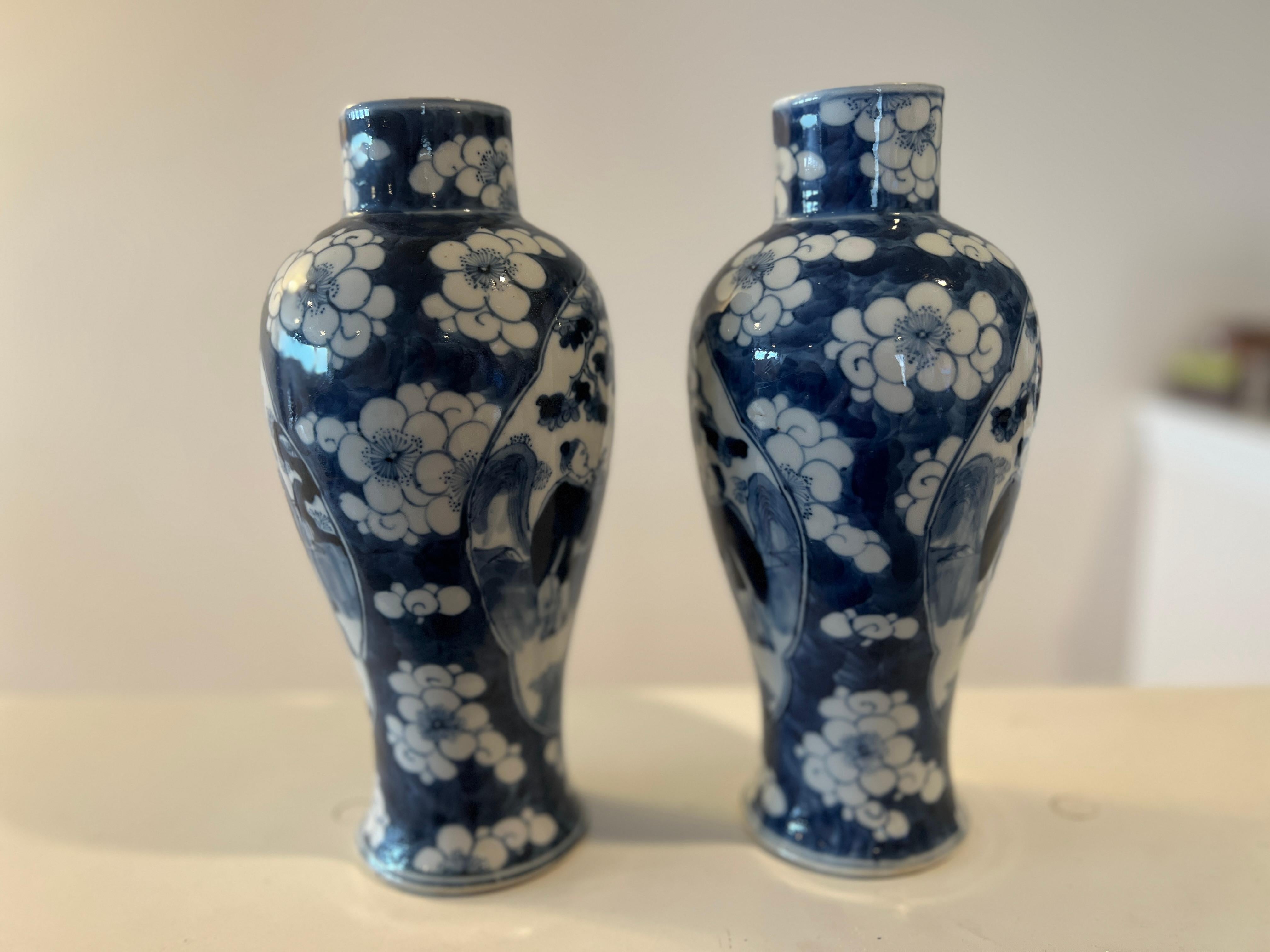 Chinese, Hongxian period circa 1915. 

A pair of Chinese export porcelain vases in a blue and white floral motif surrounding two figural emperor windows. Marked with wax seal and Hongxian mark to underside. 