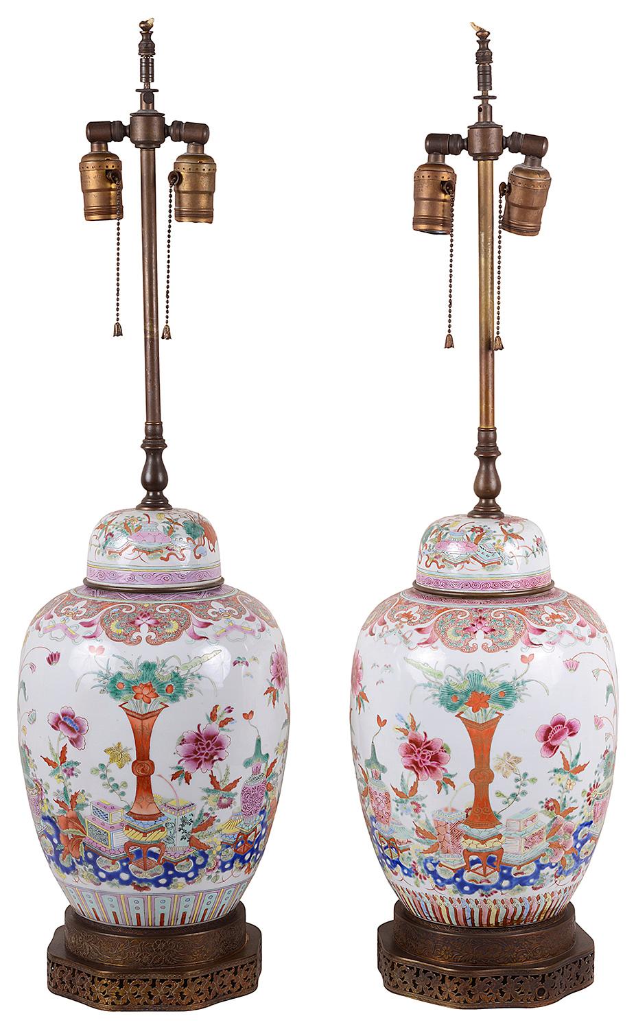 A good quality pair of 19th century Chinese Famille rose lidded ginger jar lamps, each with wonderful colorful scenes depicting vases, motifs and floral decoration, raised on pierced oriental style brass bases.