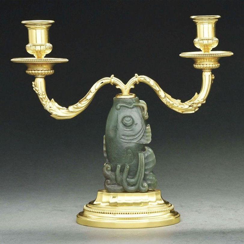 Our pair of rare two-light gilt silver candlesticks from Cartier from the early 20th century feature finely carved jade stone figures of fish.  Each 10 by 10 3/4 by 3 1/2 inches.  Marked Cartier.