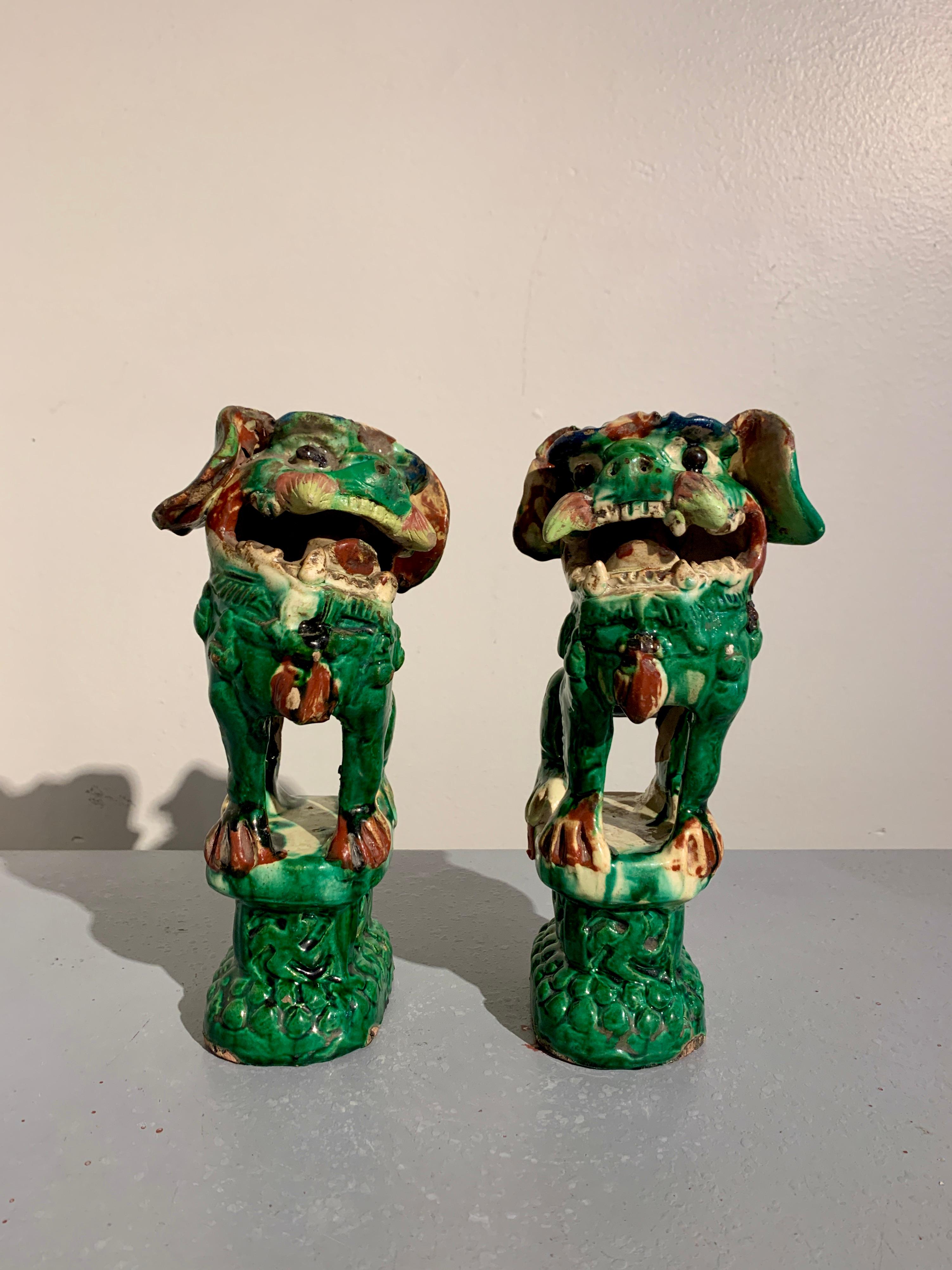 A delightful pair of Chinese glazed pottery foo dogs, Qing Dynasty, circa 1900, Wangzhai Village, Zhejiang, China. 

The charming and funky pair of foo dogs are modeled standing upon a raised plinth decorated with 