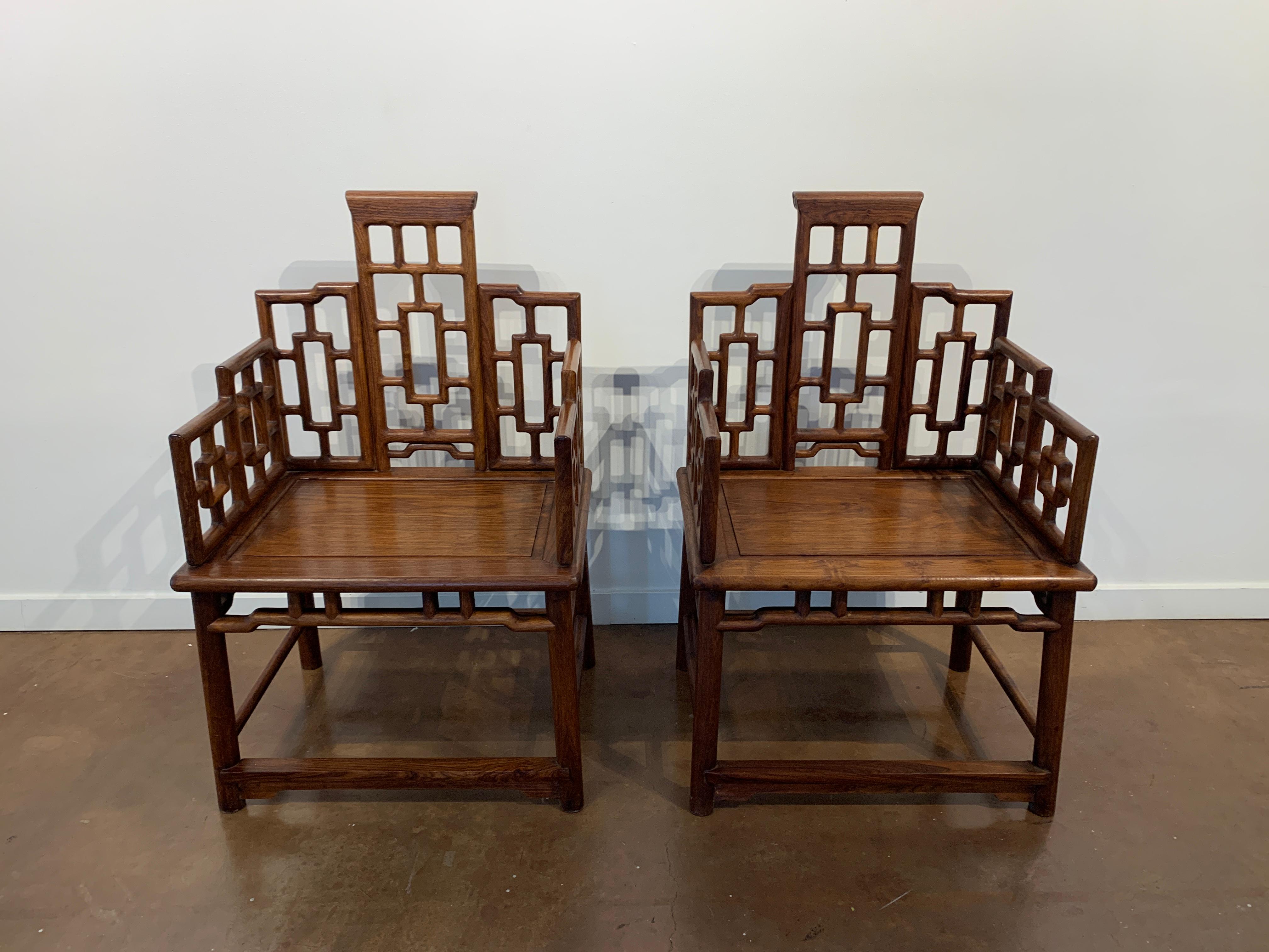 A striking pair of Chinese geometric panel hardwood armchairs, fushouyi, mid-20th century, China. 

The somewhat oversized armchairs are made from a dense and beautifully figured hardwood or reddish brown tone that displays enchanting honey