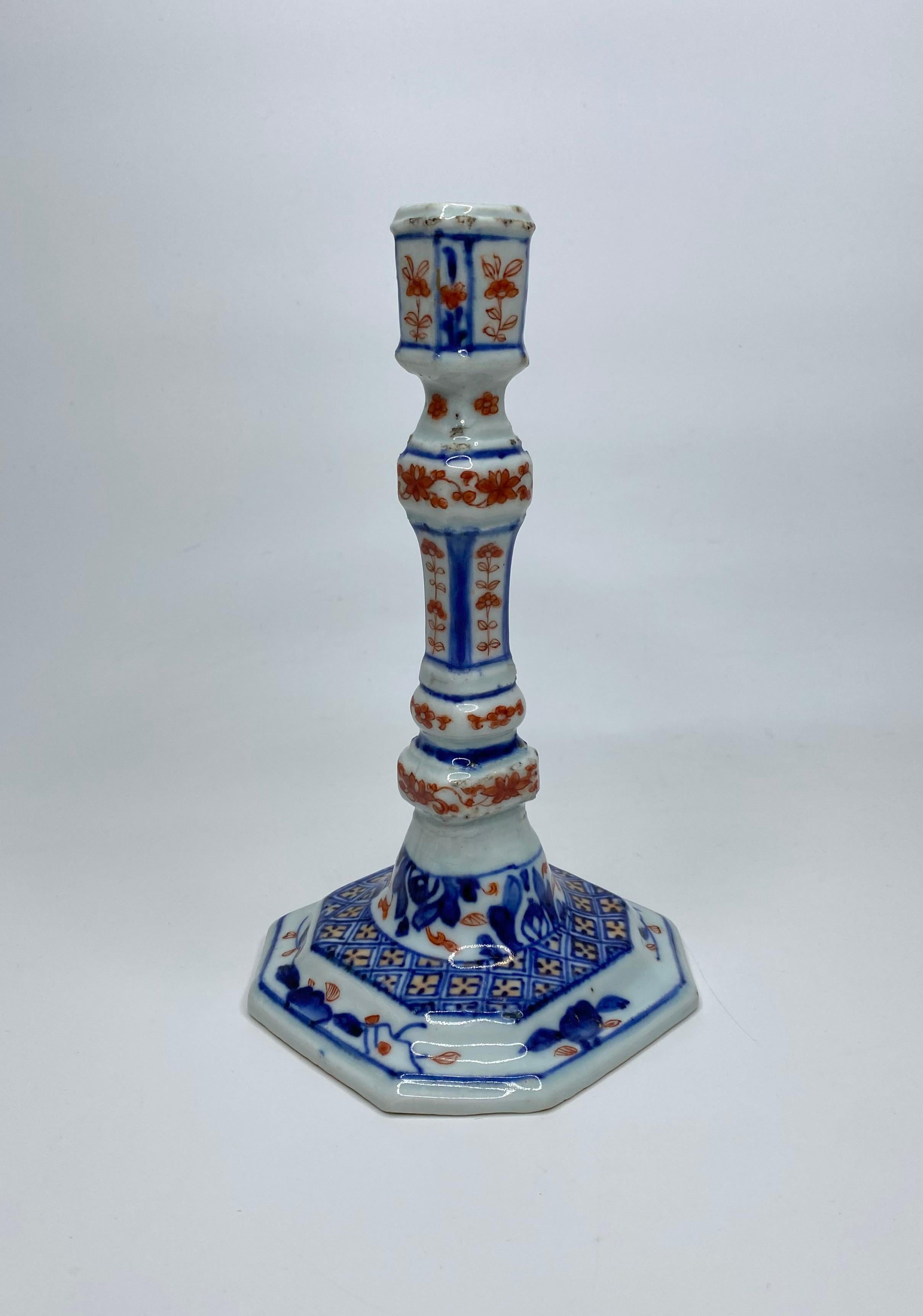 Pair of Chinese ‘Imari’ porcelain candlesticks, c. 1720, Kangxi Period. Modelled after a European silver or brass original, both candlesticks rise from a squared, and stepped, octagonal base, terminating in square sconces. Hand painted in the