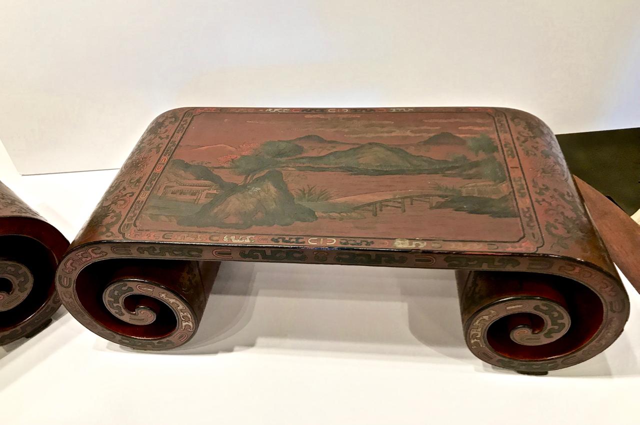 This is a very unusual pair of Chinese sang de boeuf lacquered scroll-end stands. The fine coromandel lacquer surface extends around the scrolled ends. The top surfaces depict a mountain landscape. One stands is in overall very good condition; the