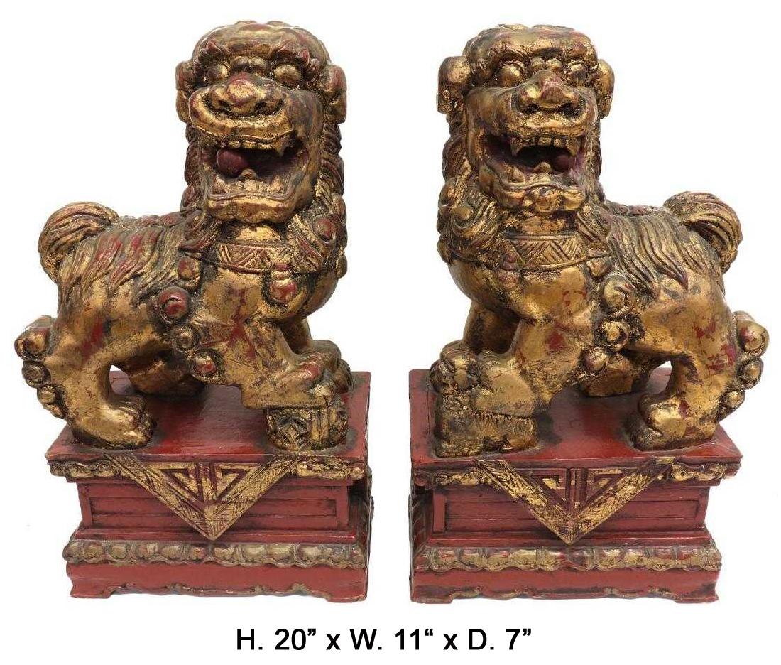 Highly decorative pair of Chinese parcel-gilt carved wood red guardian foo-lions, each with a ball and cub in hand and raised on a conforming stepped plinth. 
20th century.

 