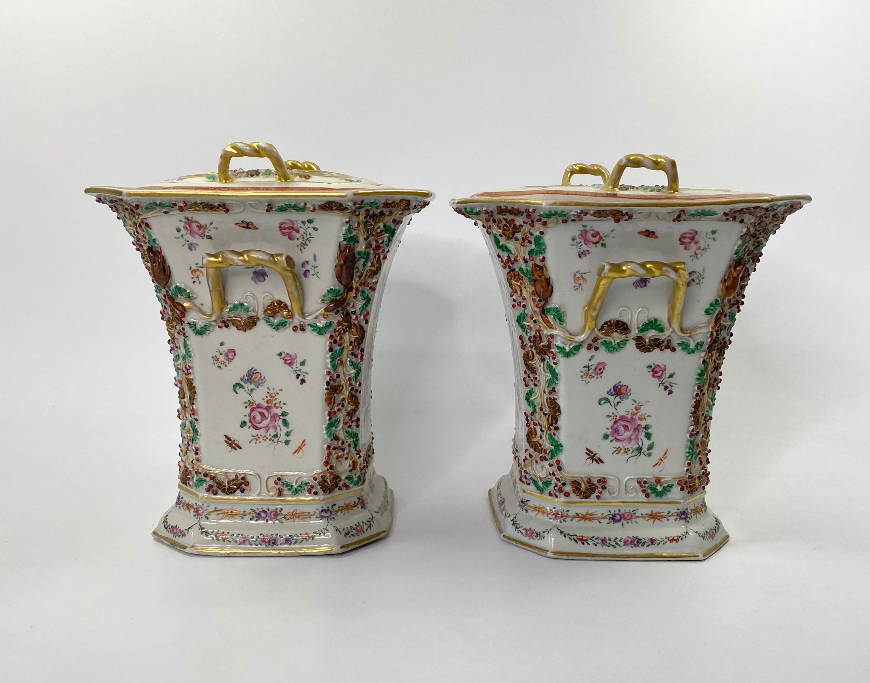 An exceptionally fine pair of Chinese porcelain bough pots and covers, Qianlong Period (1736 -1795). Hand painted in famille rose or fencai enamels, with panels of dishes of fruit upon stands, alongside vases of flowers, with insects flying above.