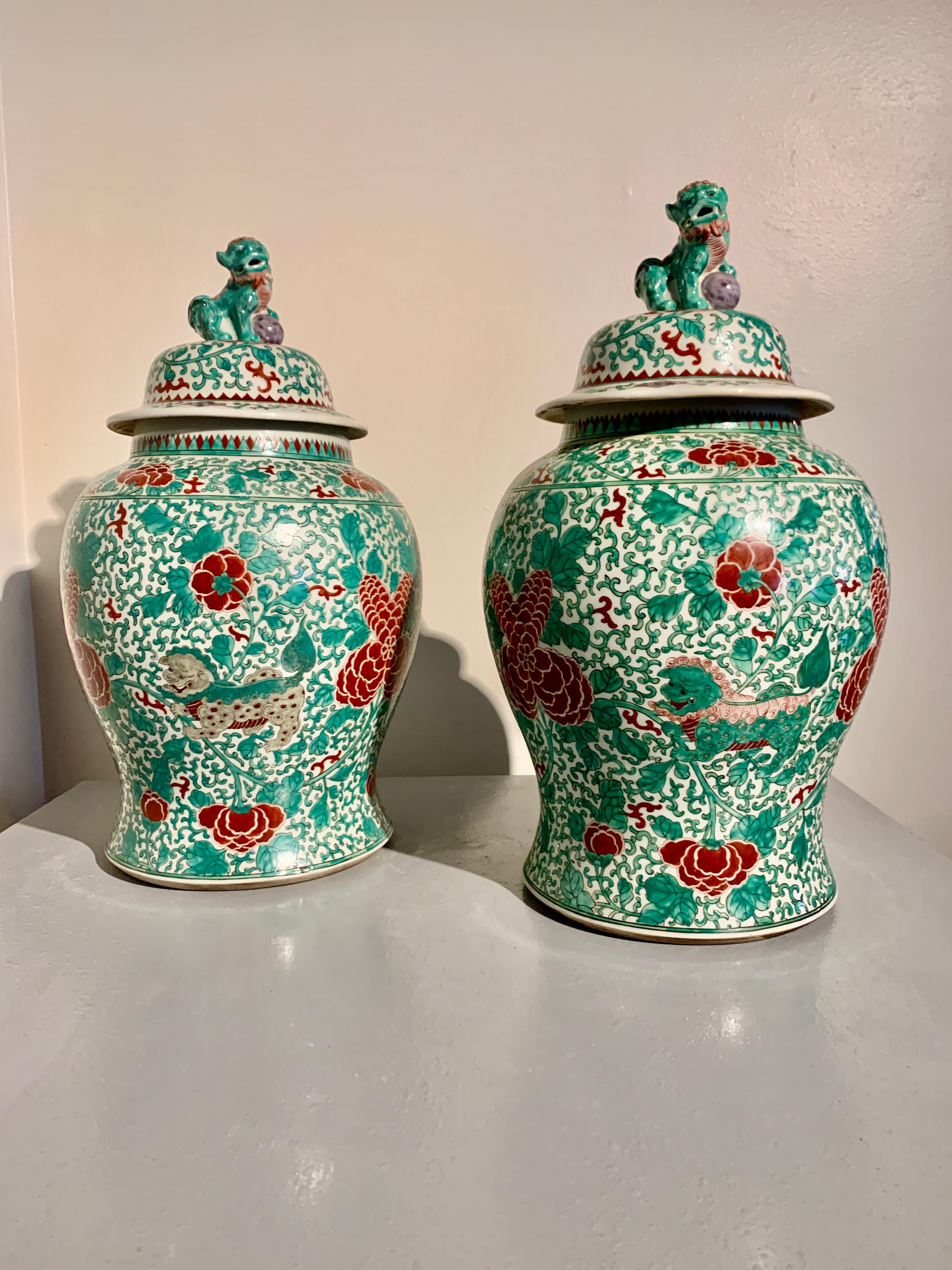 A delightful pair of Chinese famille verte enameled porcelain covered jars with foo lions, circa 1960's, China.

The jars of baluster form and painted in bold and bright famille verte enamels of primarily green and red, with areas of puce and gray.