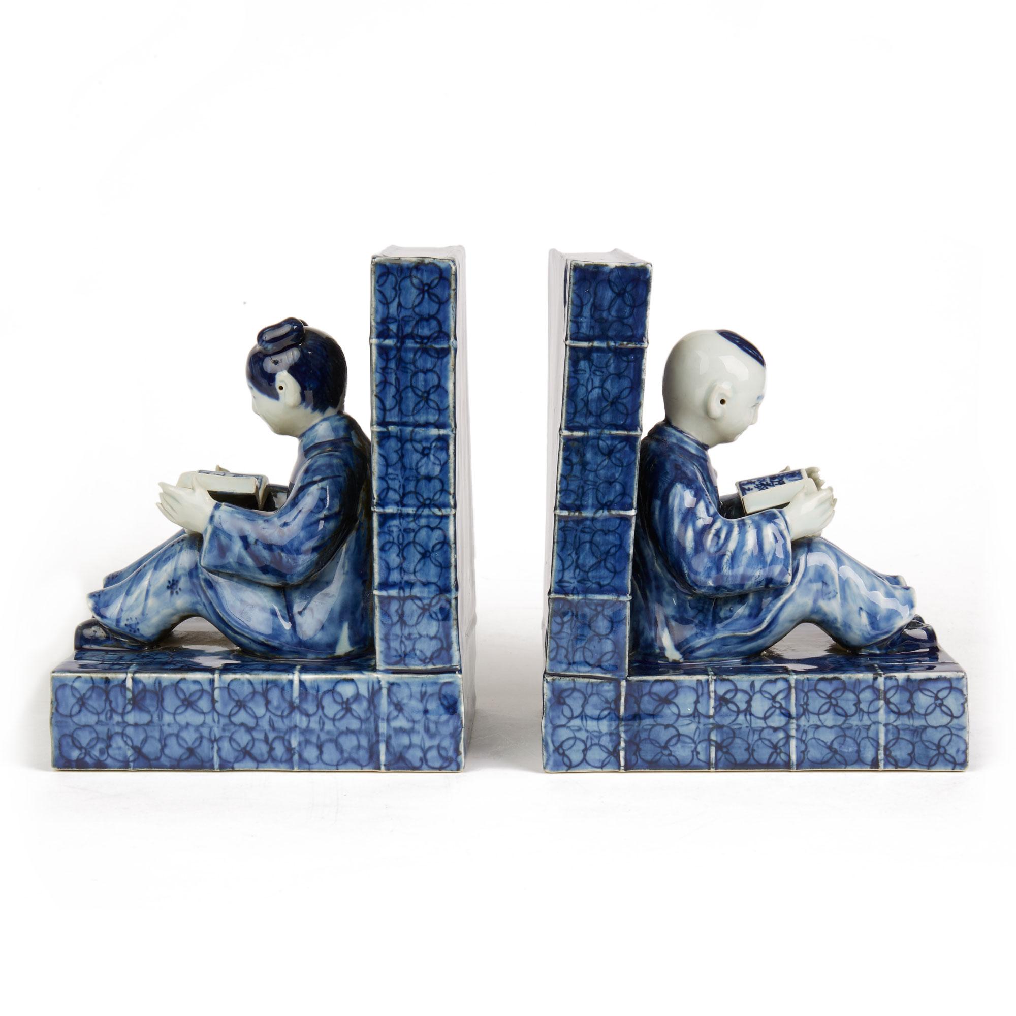 A scarce and unusual pair vintage Chinese Republic period porcelain bookends, solidly constructed and formed as two books forming an 'L' shape. The bookends are mounted with figures, one with a your seated boy reading a book and the other with a