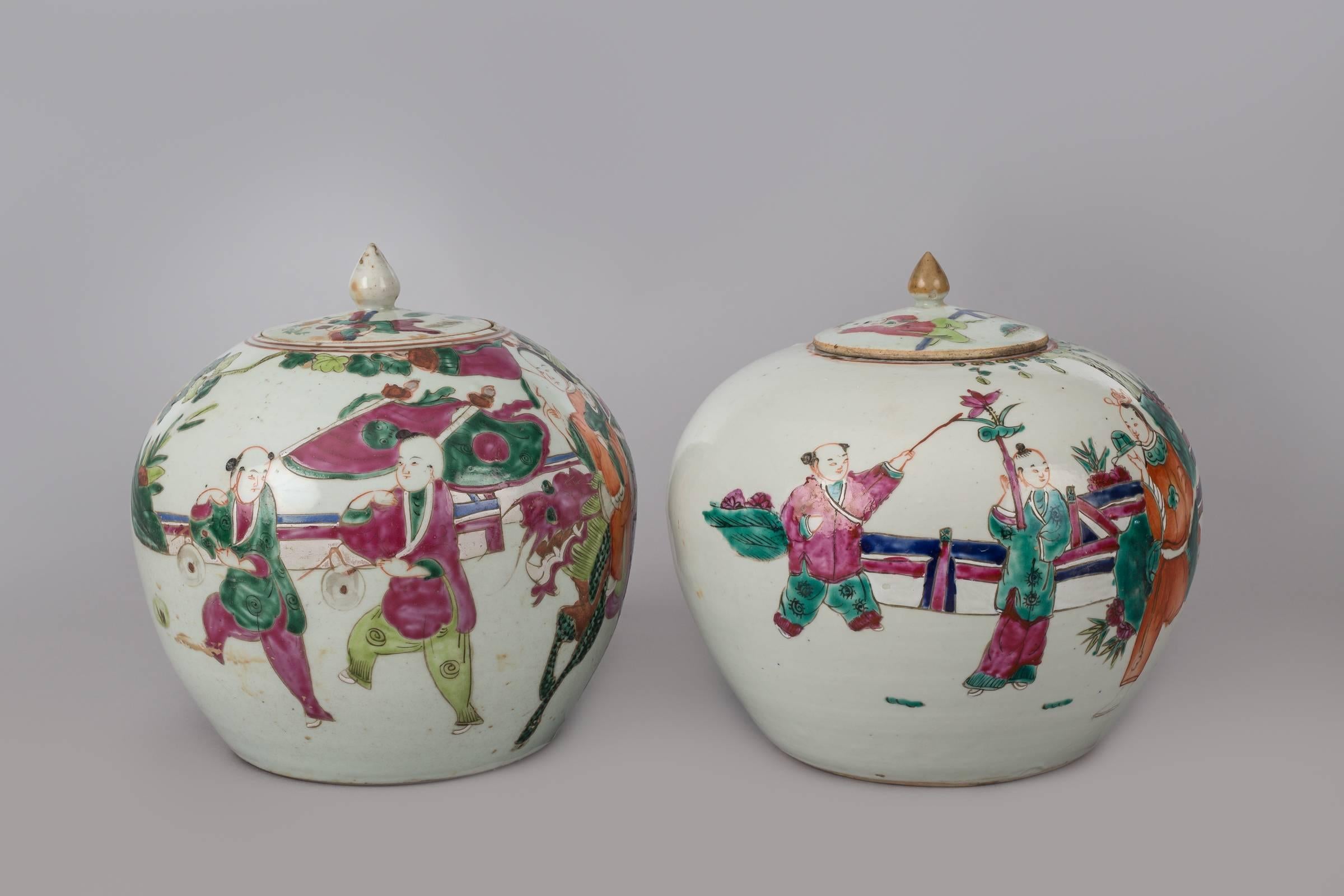 Pair of Chinese porcelain squat lidded vases decorated with figures celebrating the New Year and wearing colorful costumes, three figures are riding a horse and some are flying kites. The backs of the jars are decorated with bats.