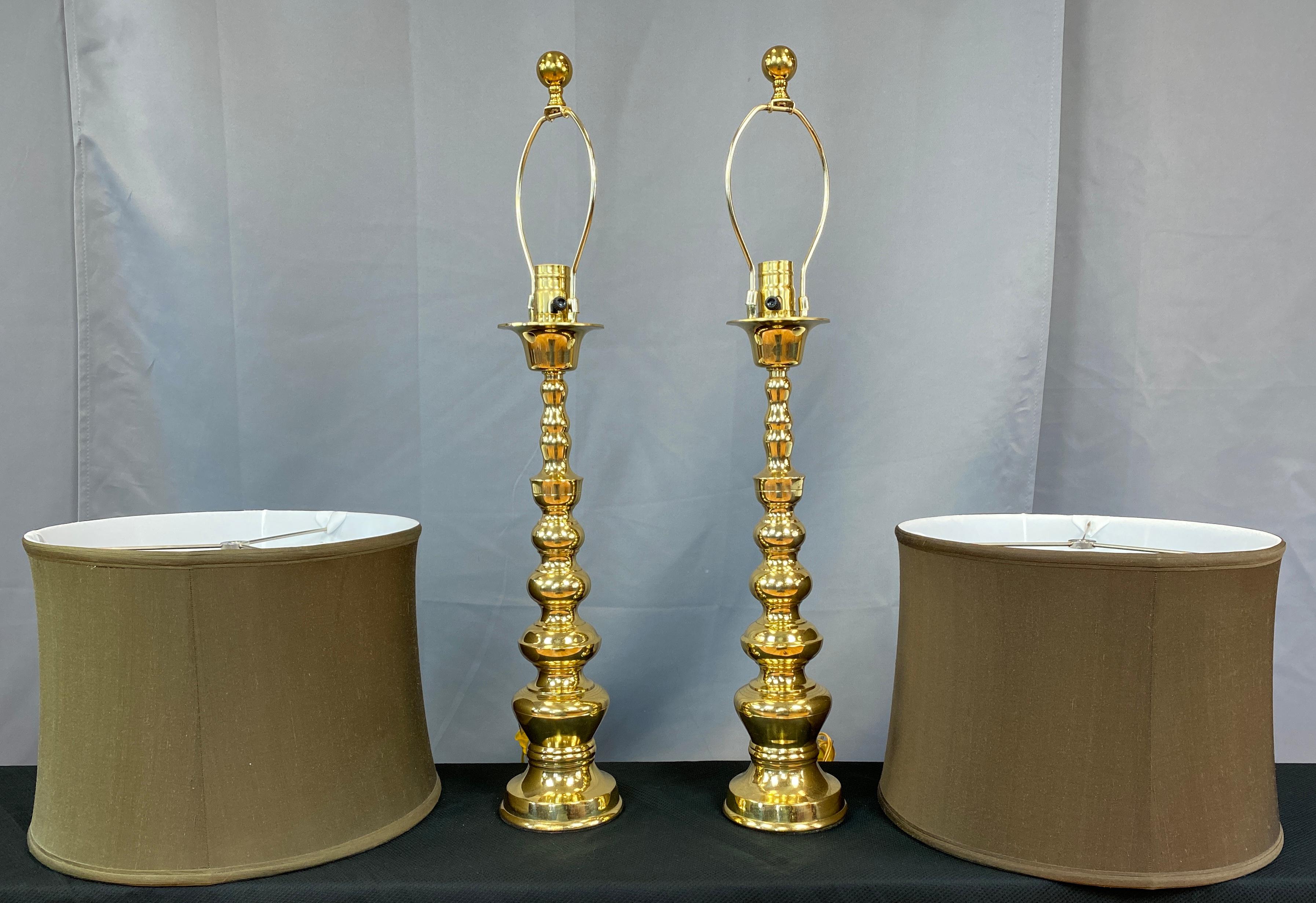 Offered here is a pair of glamorous, polished brass table lamps, with olive green shades giving you that Hollywood Regency vibe. 
Made in Japan, they have round weighted bases with graduating shapes rising up from it, stopping right below
a drip