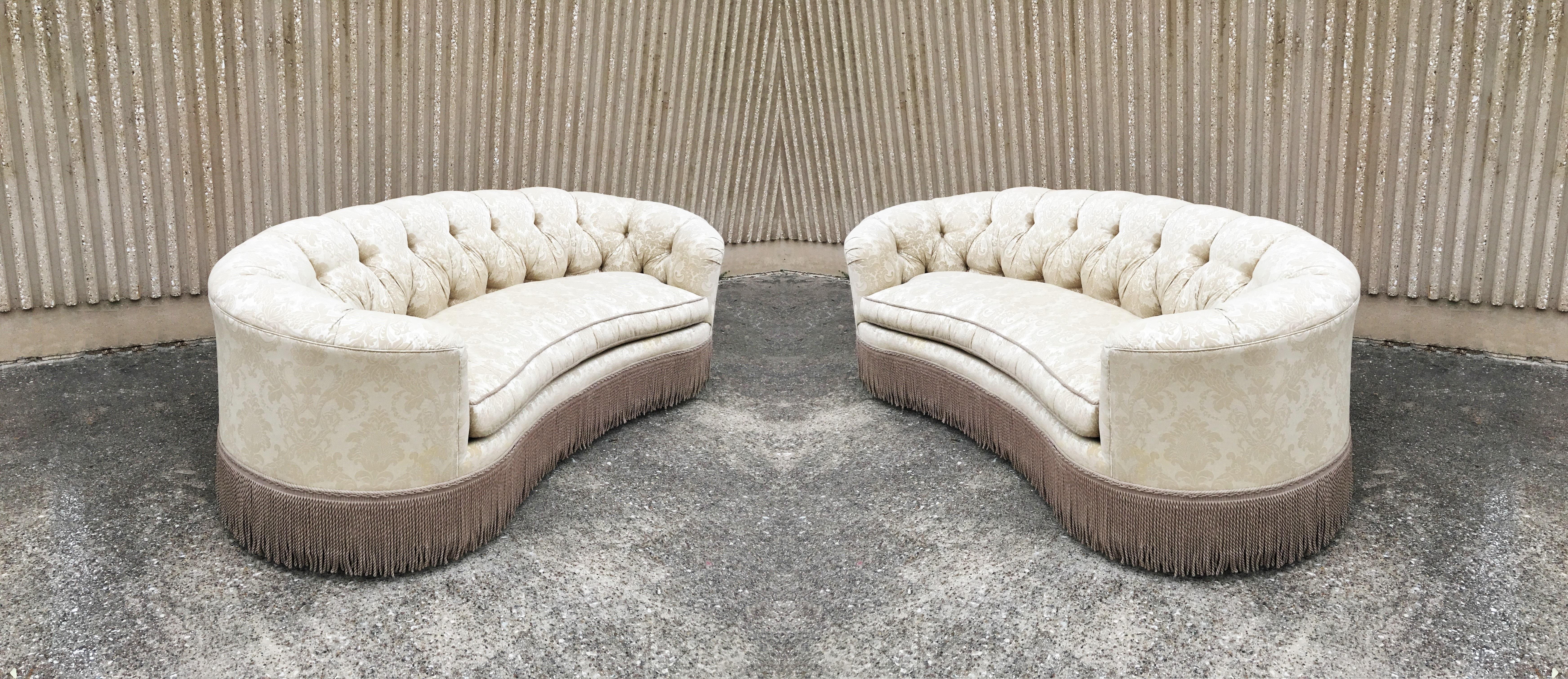 An exceptional pair of vintage kidney bean shaped sofas are the perfect blend of traditional style with modern touch. The sofas have curved backs and a thick body, the clean seat cushions complement the thick texture of the tufted back that flow