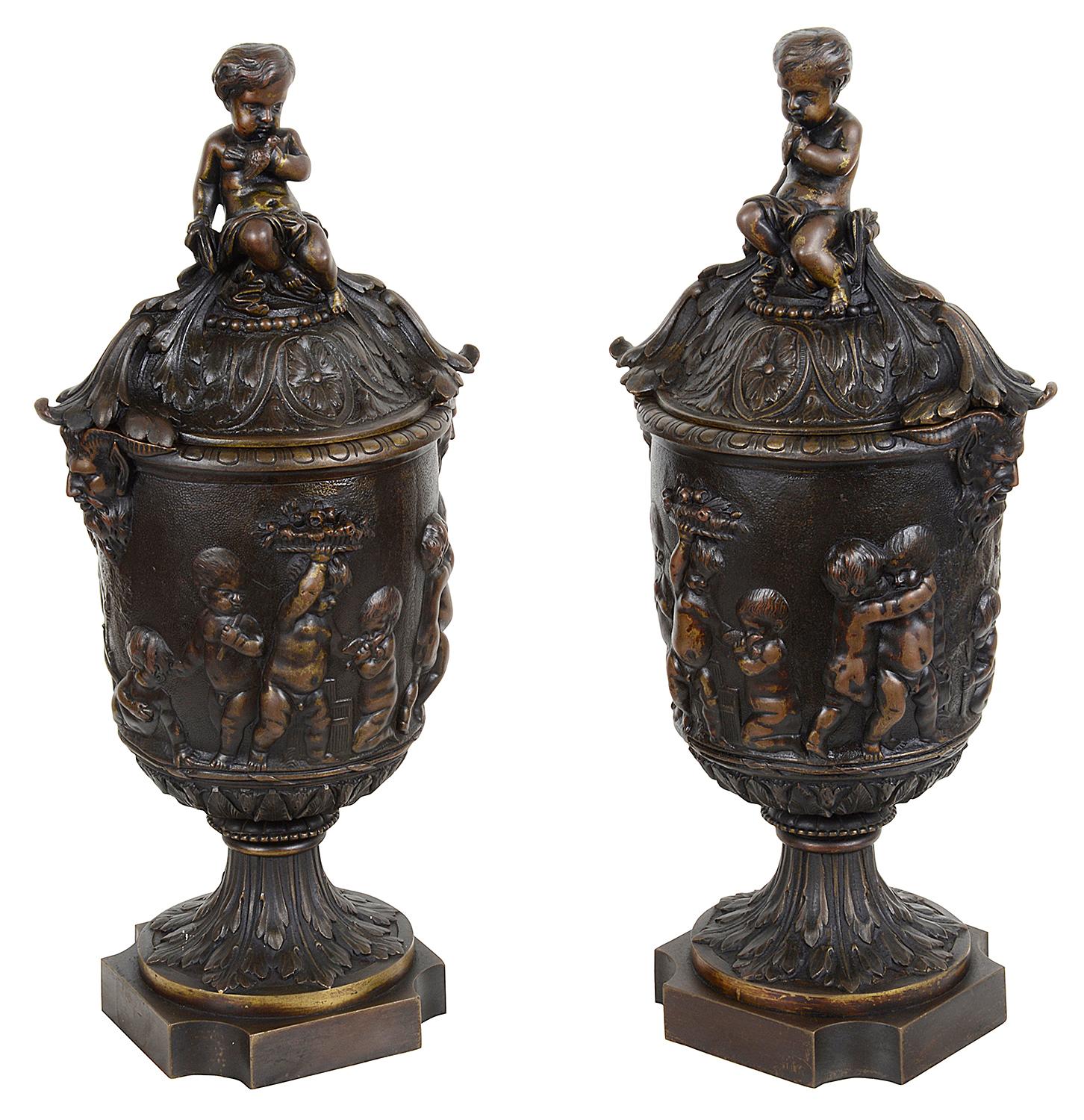 A good quality pair of French 19th century classical lidded bronze urns each with seated putti atop scrolling foliate decoration. Scenes of Bacchus influenced cherubs playing above pedestal bases.
