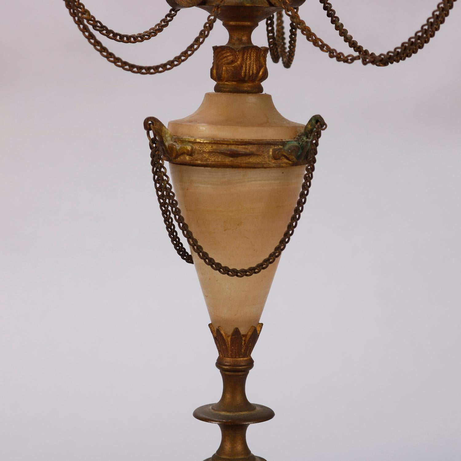 A pair of classical candelabra offer gilt metal foliate form arms with alabaster bobeche and draping chain surmounting drape decorated alabaster urn form column raised on stepped base with cast paw feet, circa 1880

Measures: 18.5