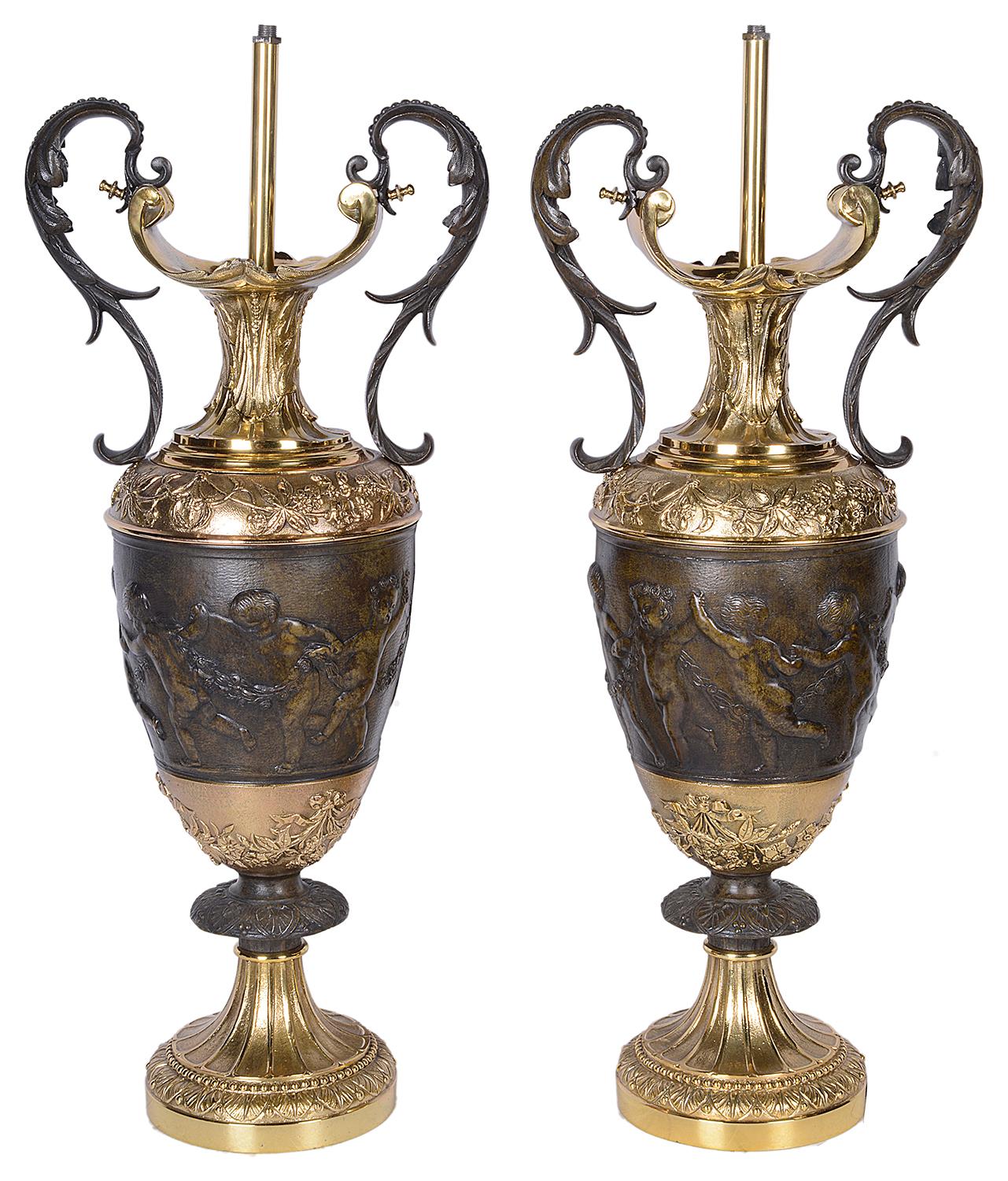 A good quality pair of classical Italian style bronze and gilded ormolu two handle vases / lamps, each having scrolling foliate decoration with dancing cherubs holding hands.