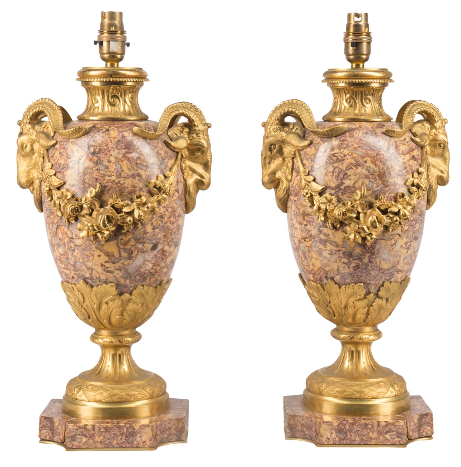 A good quality pair of French 19th century gilded ormolu and marble urns, each with classical ram's head mounts and swags.