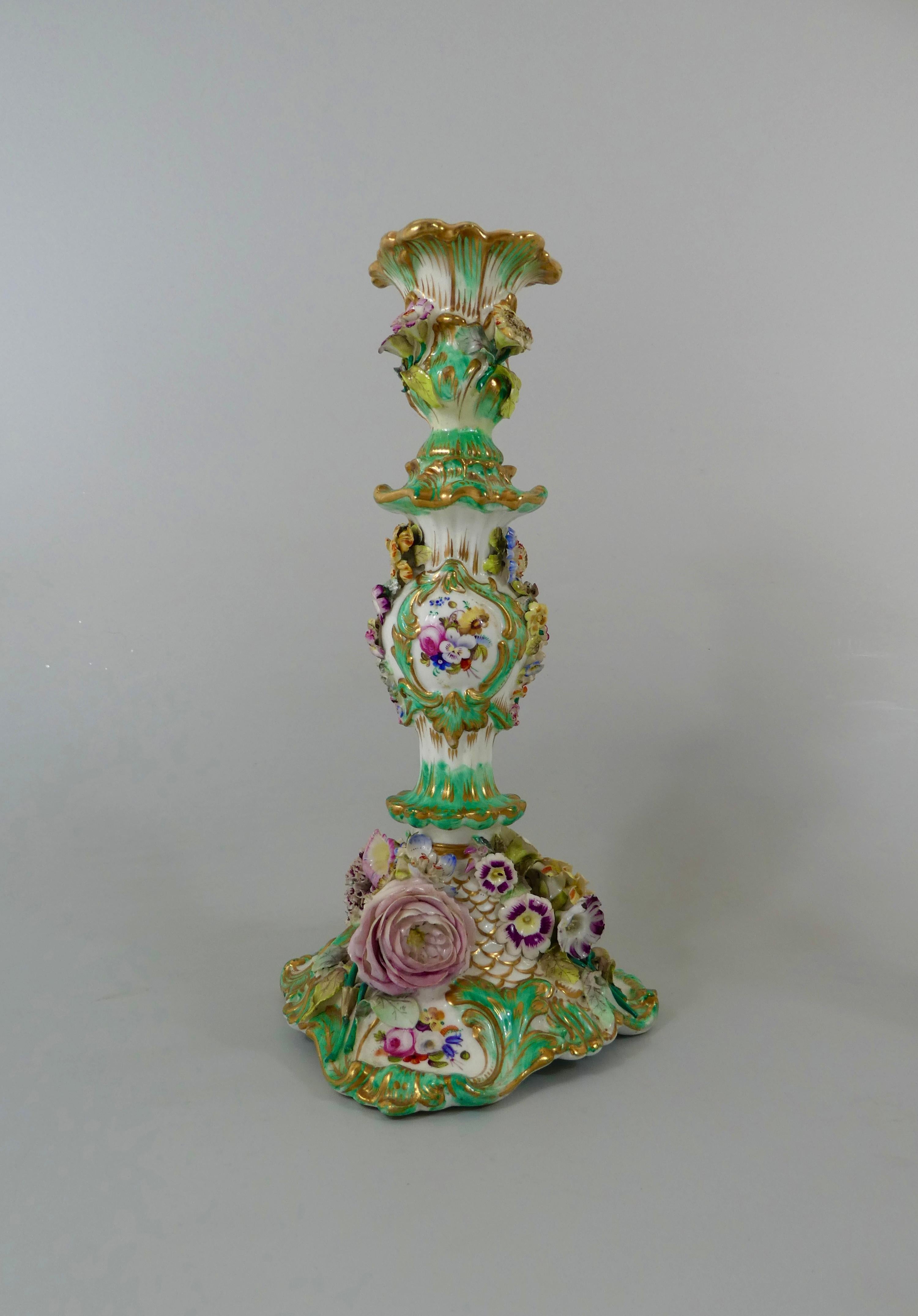 Pair of Coalport Porcelain candlesticks, circa 1830. The Rococo scroll moulded candlesticks, finely painted with panels of flowers, within green and gilt borders. Encrusted with a profusion of brightly enameled flowers, of various sizes.
Measures: