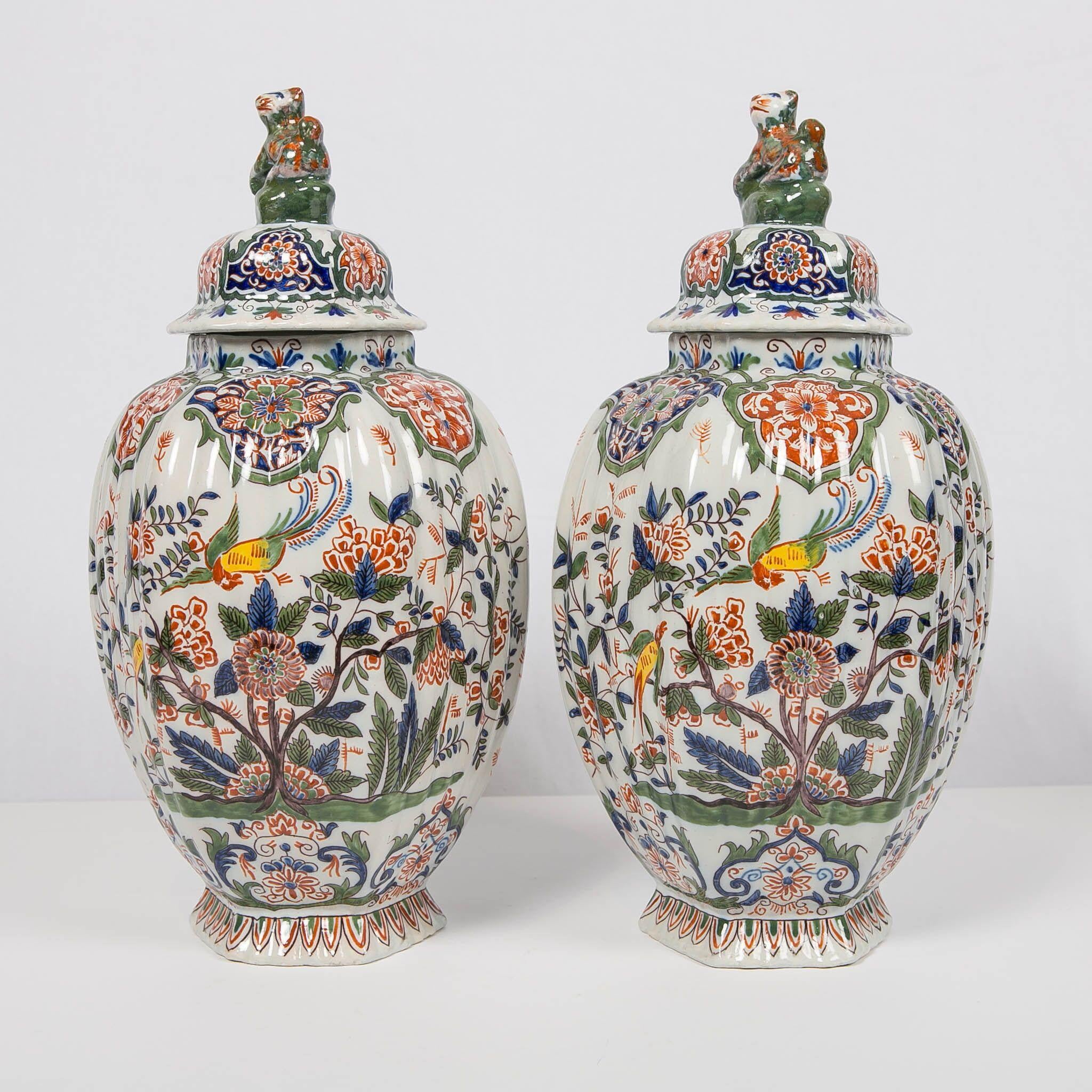 We are pleased to present this lovely pair of Dutch delft polychrome covered jars. They are painted in the cashmere palette of iron-red, moss green, and cobalt blue, with accents of bright yellow. The form of the jars is octagonal, and the surface