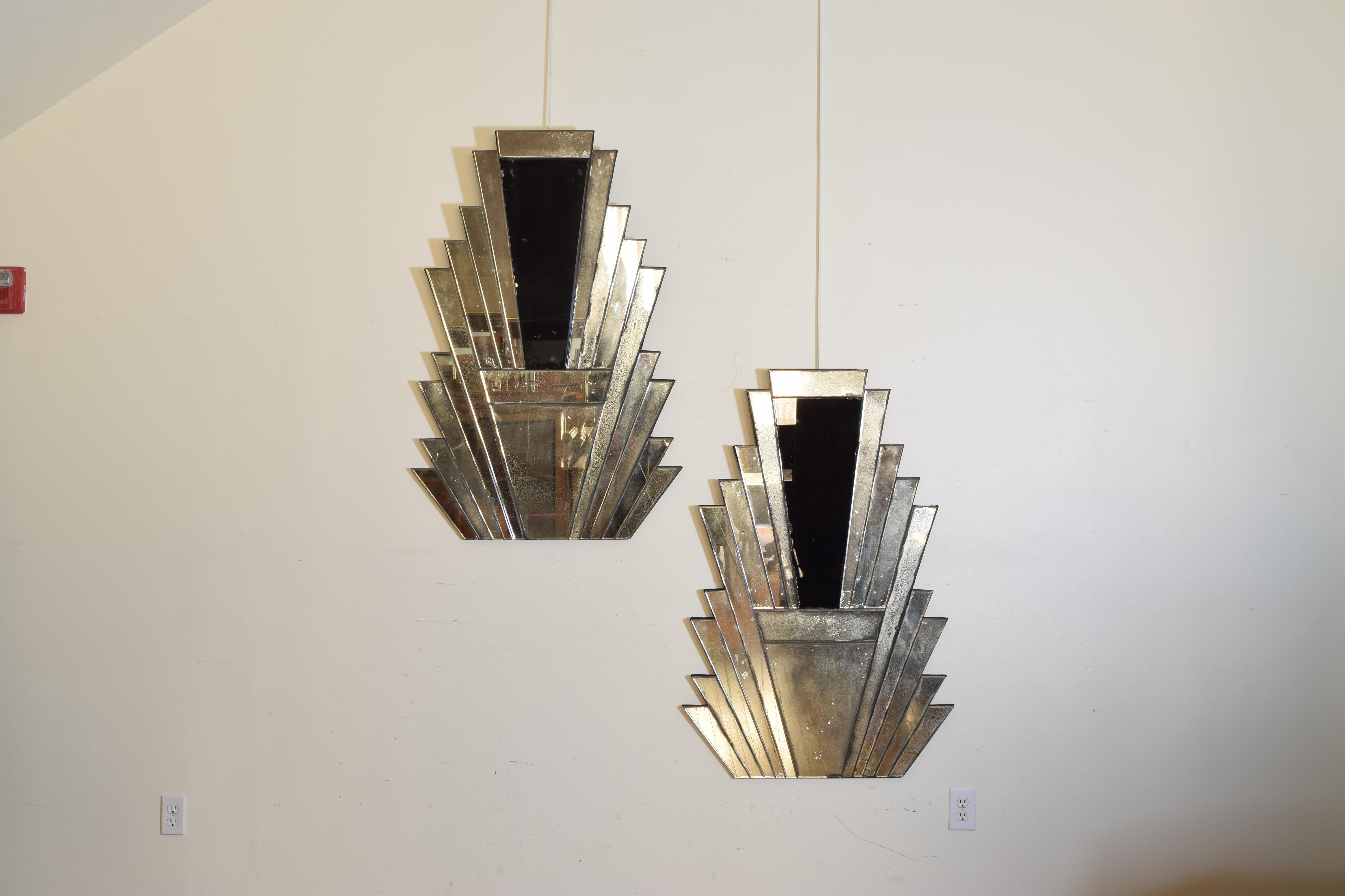 The mirrors constructed of a series of separate layered mirrored pieces stacked and surrounding larger upside down triangular pieces of tempered glass, the backs are covered in black velvet and retain original velvet wrapped hanging wires.