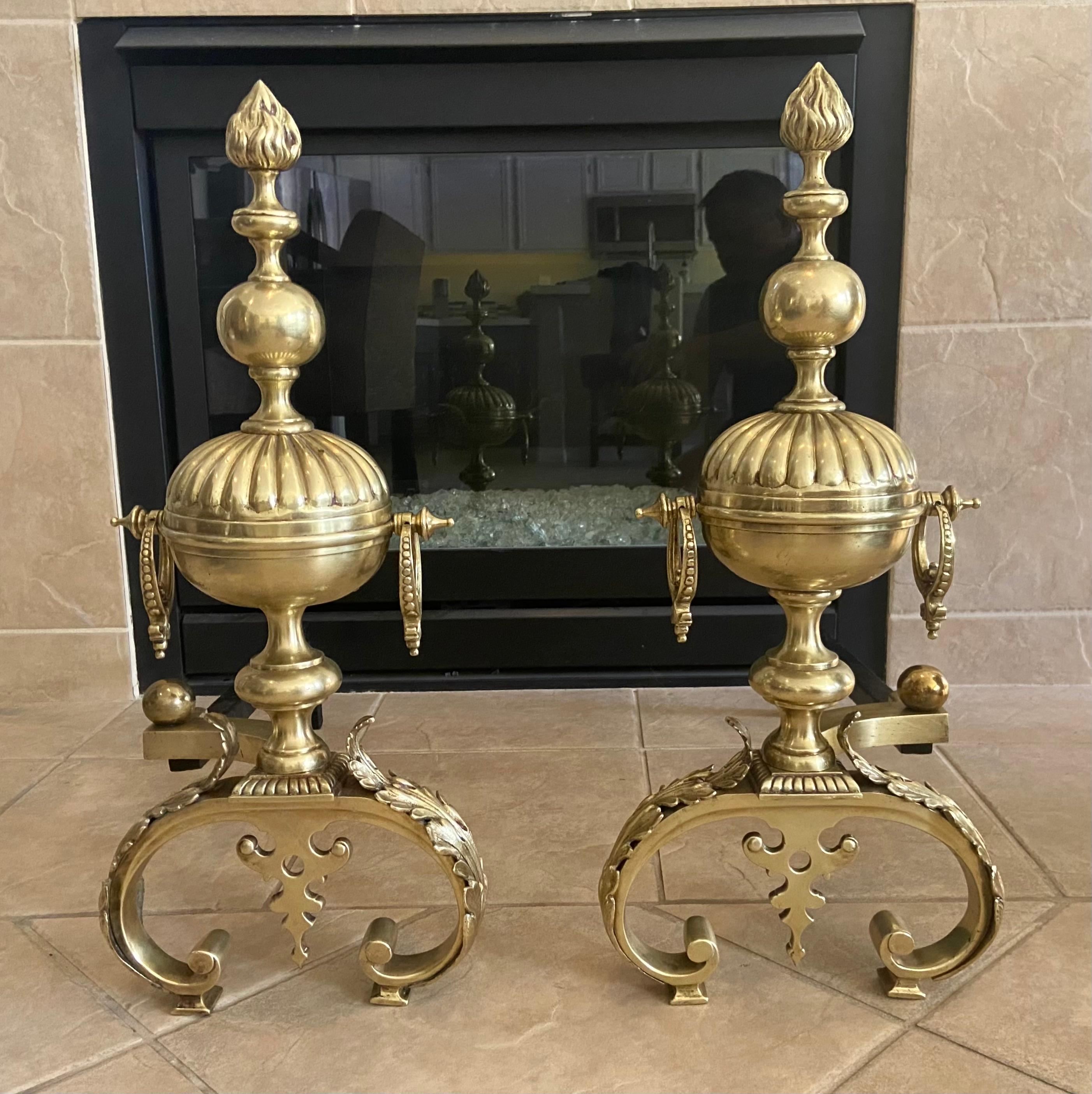 Pair of 19th century brass neoclassic style baluster shaped andirons with ball, flame and acanthus motif. Made of solid heavy brass/ bronze, with expert workmanship and fine detailing throughout. A classic silhouette that can blend with both