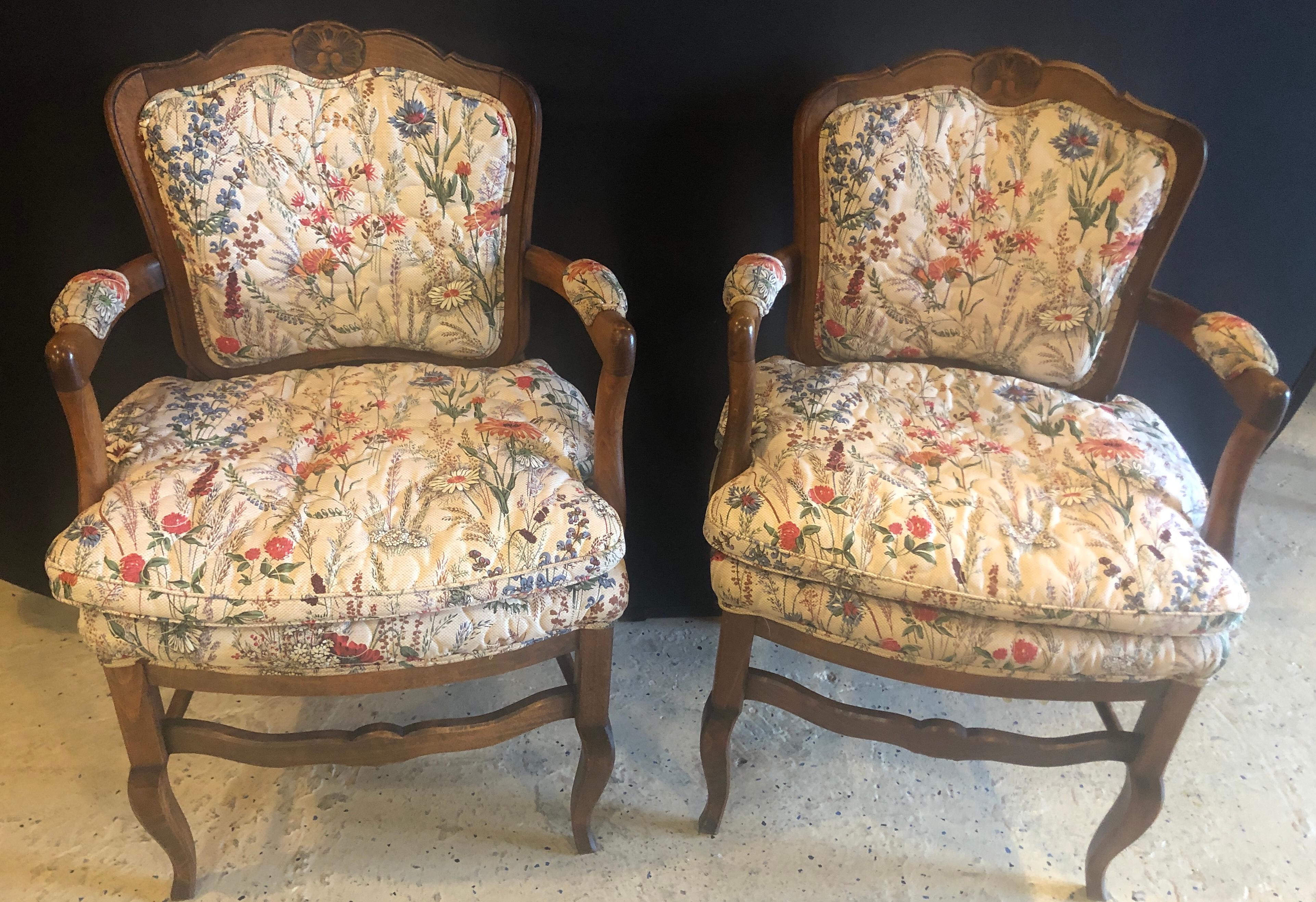 An elegant pair of country French boudoir Louis XI style fauteuils or armchairs. The chairs feature a hand-quilted upholstery and is made of walnut wood. The off -while floral print will brighten and add statement to any living environment.