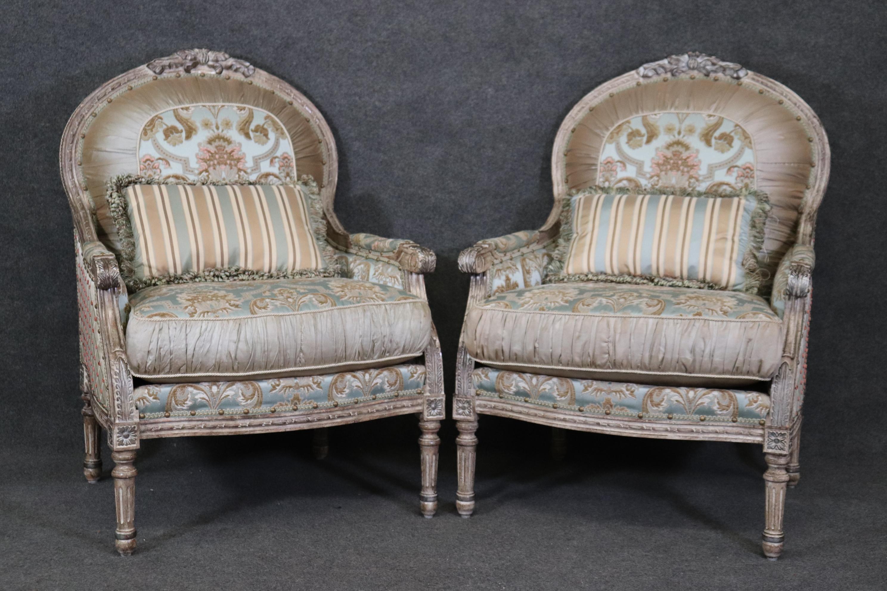  This is one of two pair available listed separately. This is a gorgeous pair of custom-upholstered French Louis bergere chairs or club chairs with gorgeous creme painted distressed finished frames and silver details on some of the carved areas. The