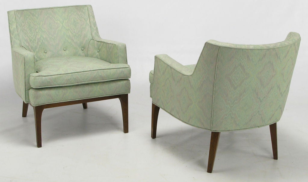 Clean lined pair of Classic club chairs in aquamarine and lavender print silk blend upholstery. Walnut wood legs with sculptural front skirt and radiused corner legs. Loose seat cushion, and button tufted lower back with nice single welt detailing.