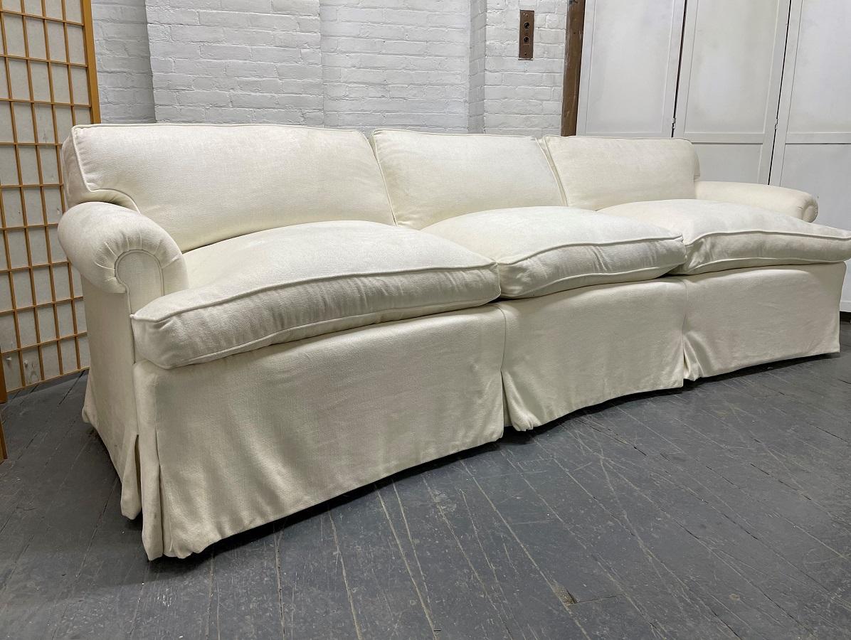 Pair of custom design three-seat down cushioned sofas. These high quality upholstered sofas have down cushions with scrolled arms, skirted, with hidden wood legs.