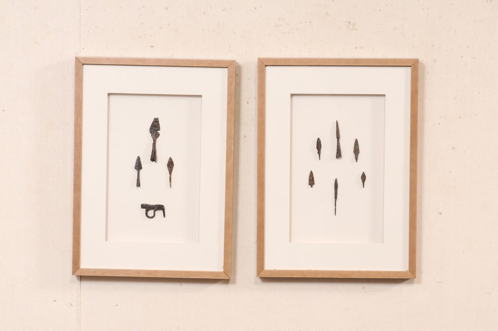 Paire d'œuvres d'art murales encadrées d'artefacts romains. Cette paire de suspensions murales est composée d'artefacts romains qui ont été décorativement présentés dans des boîtes d'ombres en bois naturel encadrées avec du papier blanc doux, ce qui