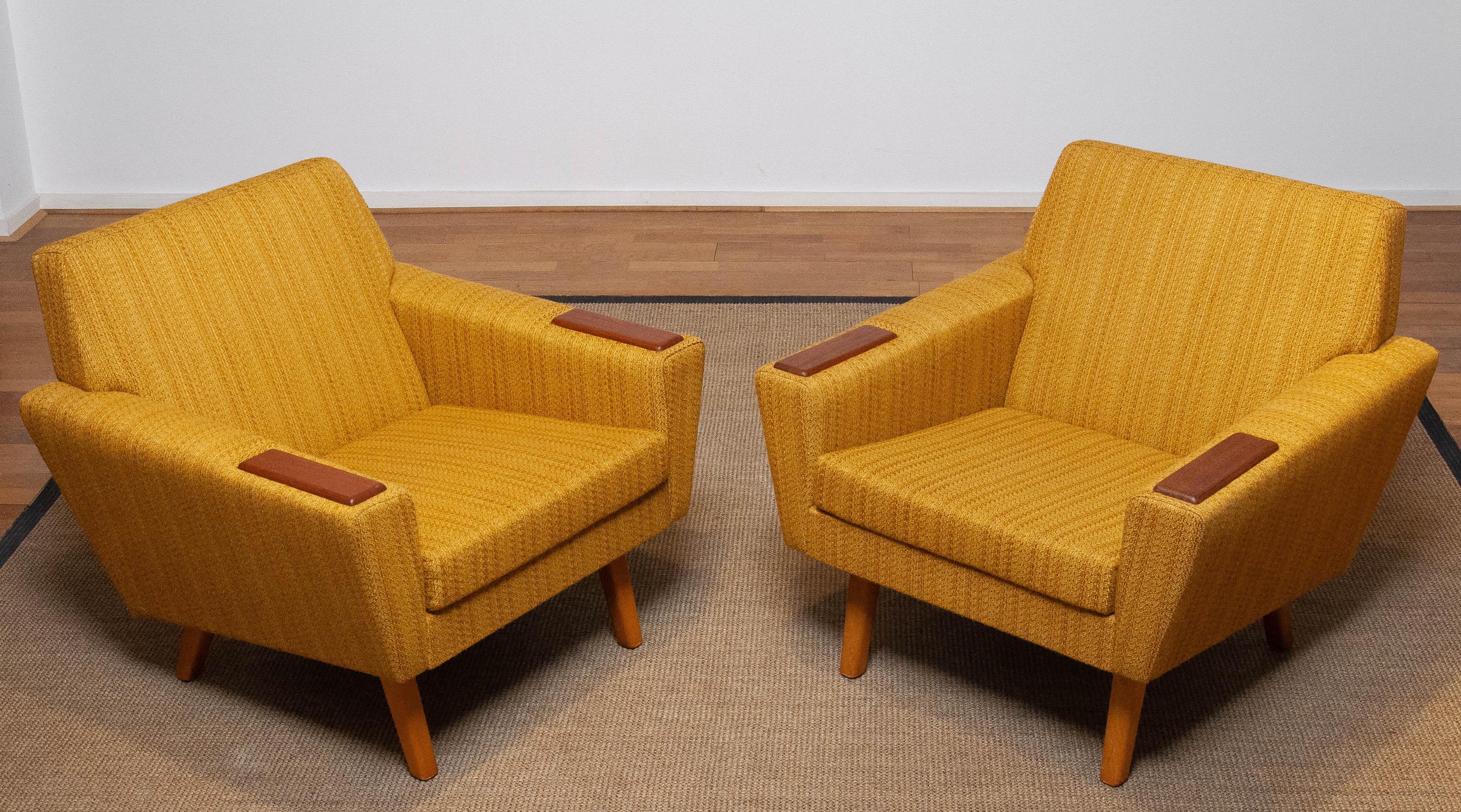 Two absolutely beautiful and typical Scandinavian mid century lounge chairs in yellow / ochre and a little brown blended colored woolen fabric in complete original condition. These chairs both supports and sits very good and is in allover very good