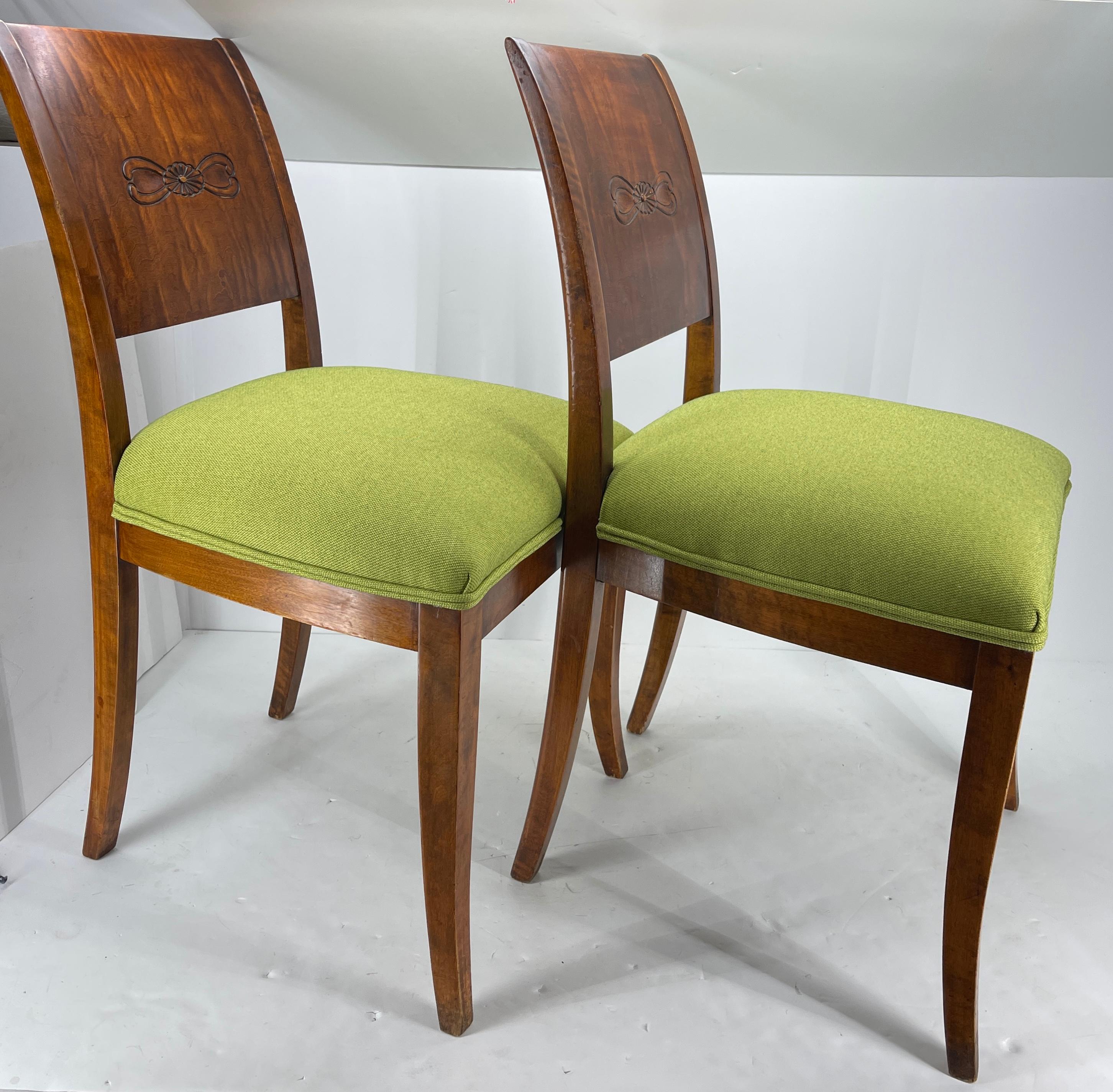 A set of Two Danish Biedermeier side chairs with beautiful carved wood design. This pair of chairs has been newly reupholstered with grass green Knoll fabric. The chairs are as comfortable as they are beautiful. The carving highlights the period and