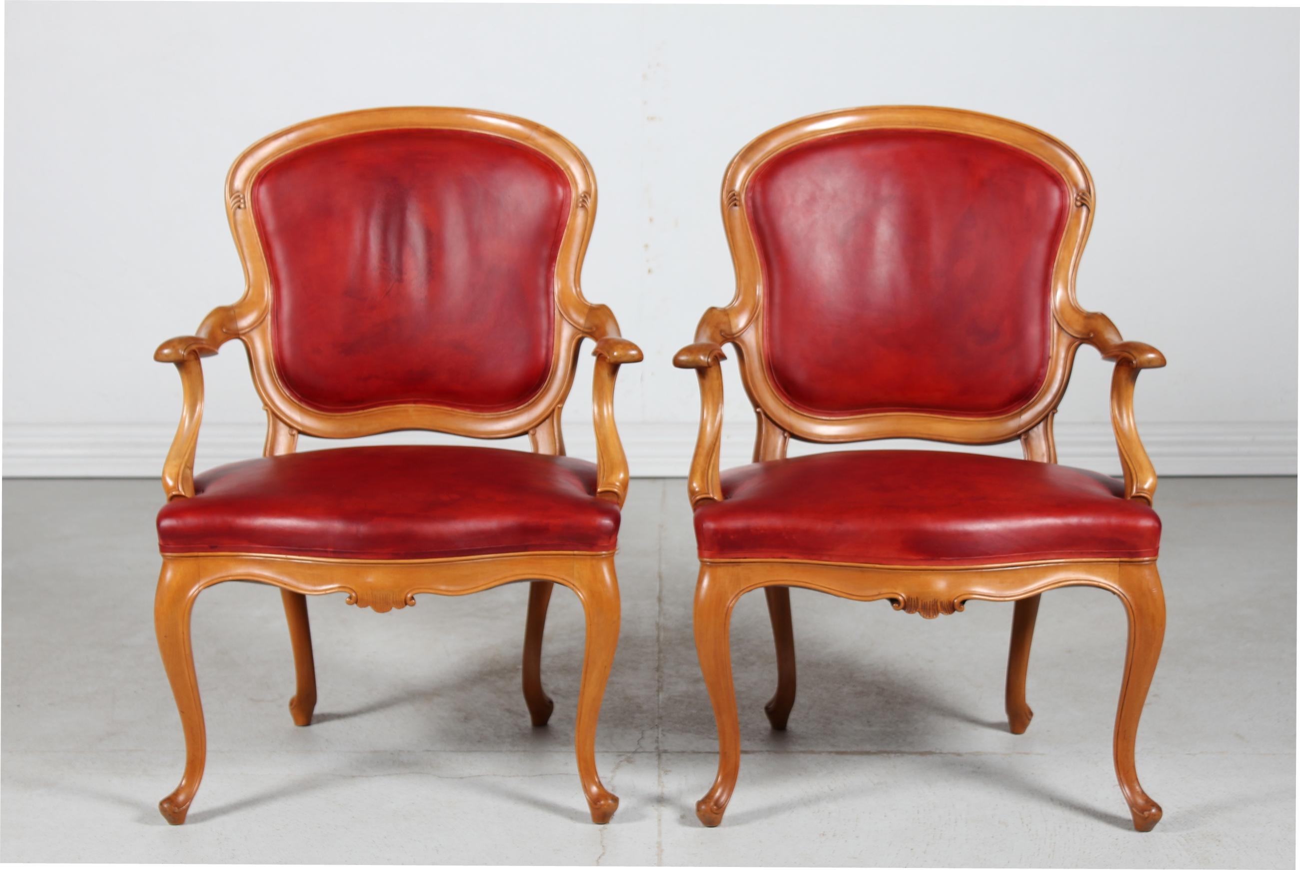 Paire de fauteuils rococo danois en noyer recouvert de cuir aniline rougeâtre patiné.
Fabriqué et sculpté à la main par un maître charpentier danois  ca. 1880. 
La tapisserie d'ameublement, qui date de plus tard (dans les années 1980, nous pensons),